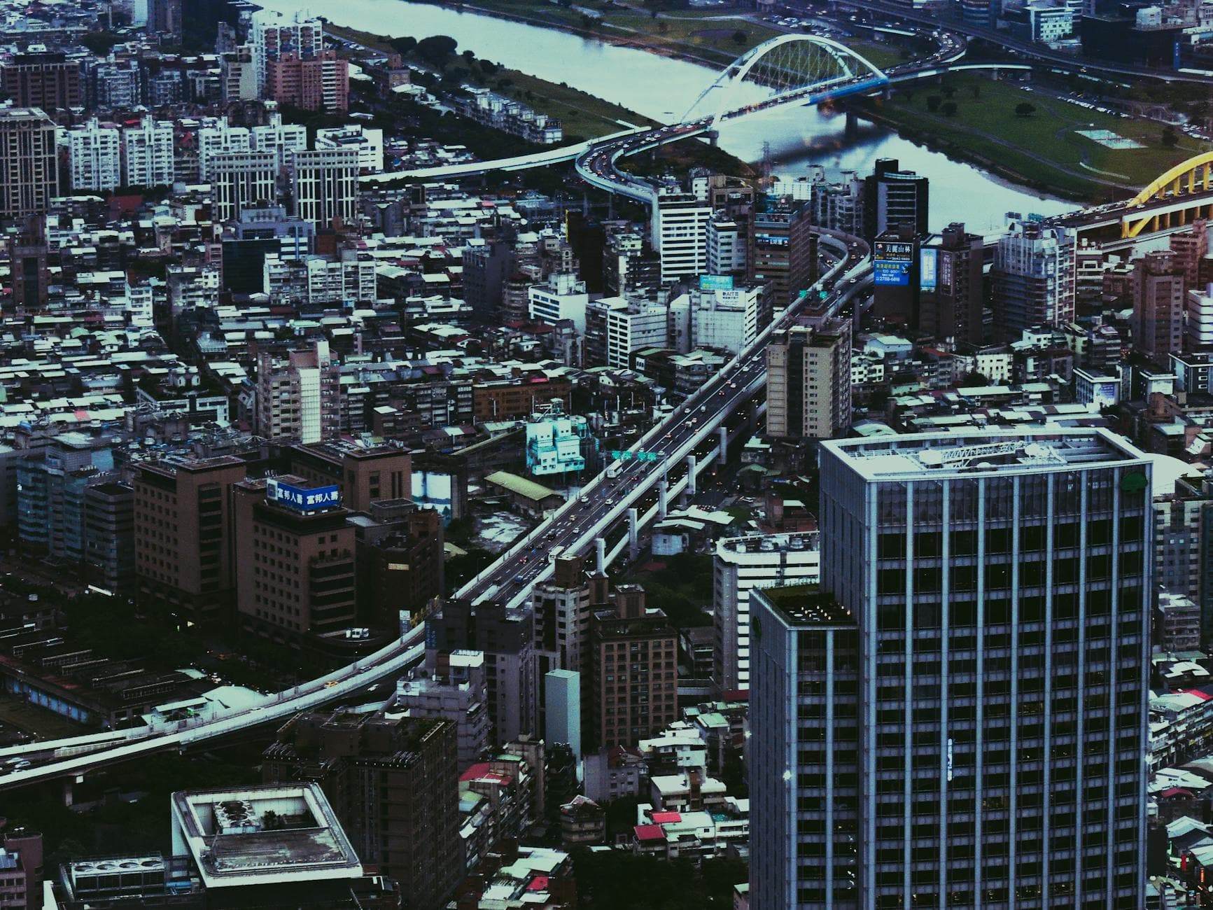 Aerial view of a bustling city with skyscrapers, bridges, and urban infrastructure.