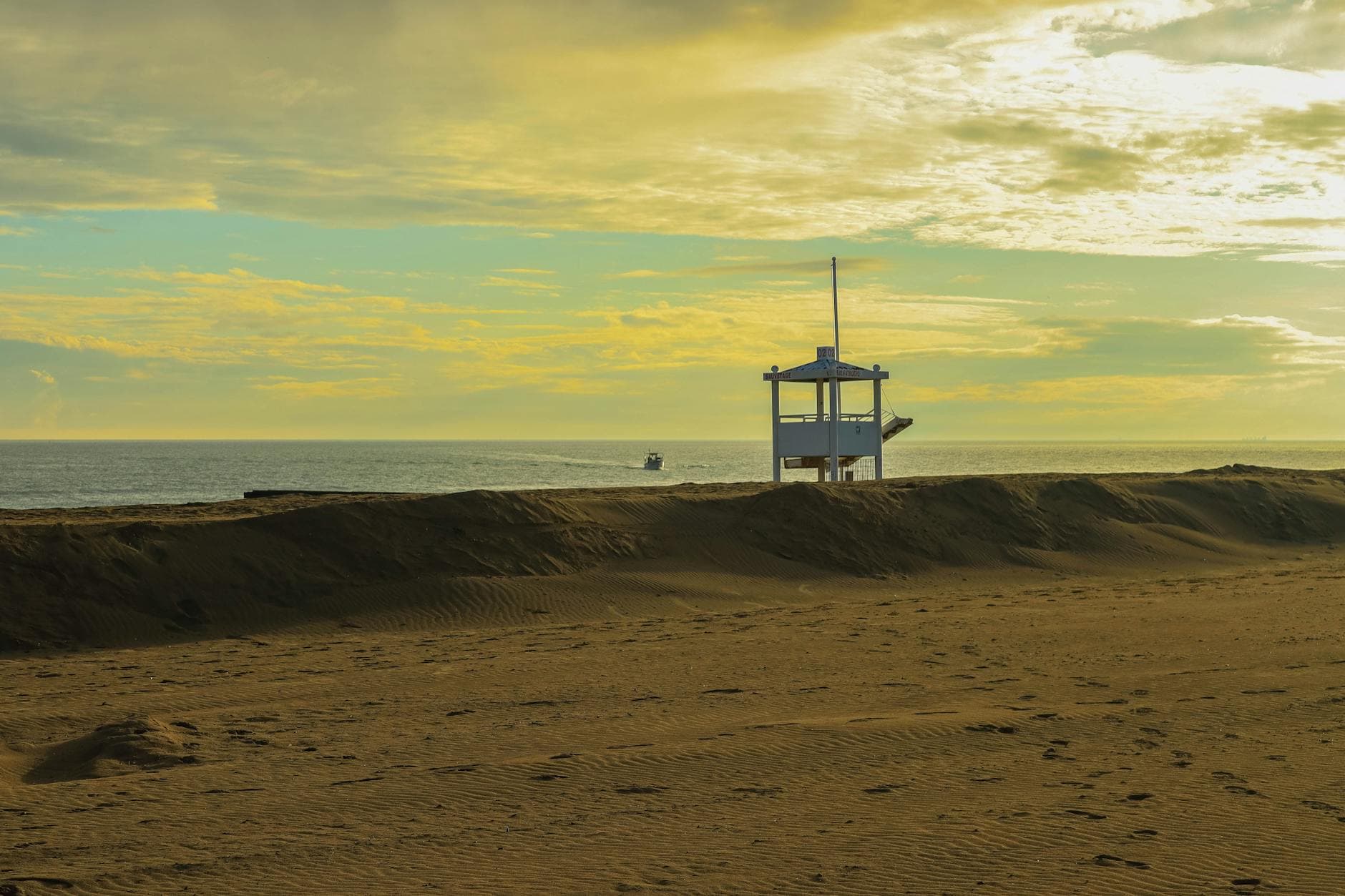 Peaceful beach scene featuring a lifeguard tower overlooking the ocean at sunset with a vibrant sky.