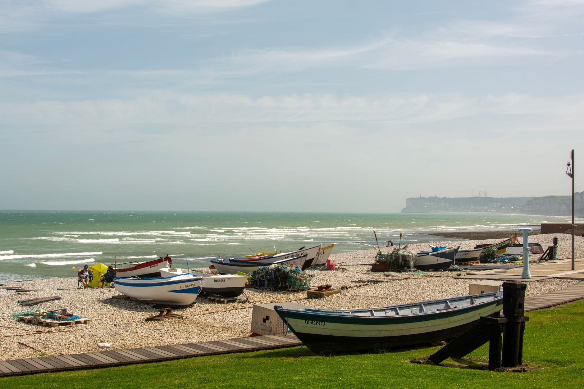 Fishing boats on a pebble beach in Yport, Normandy, France with coastal cliffs in the background.