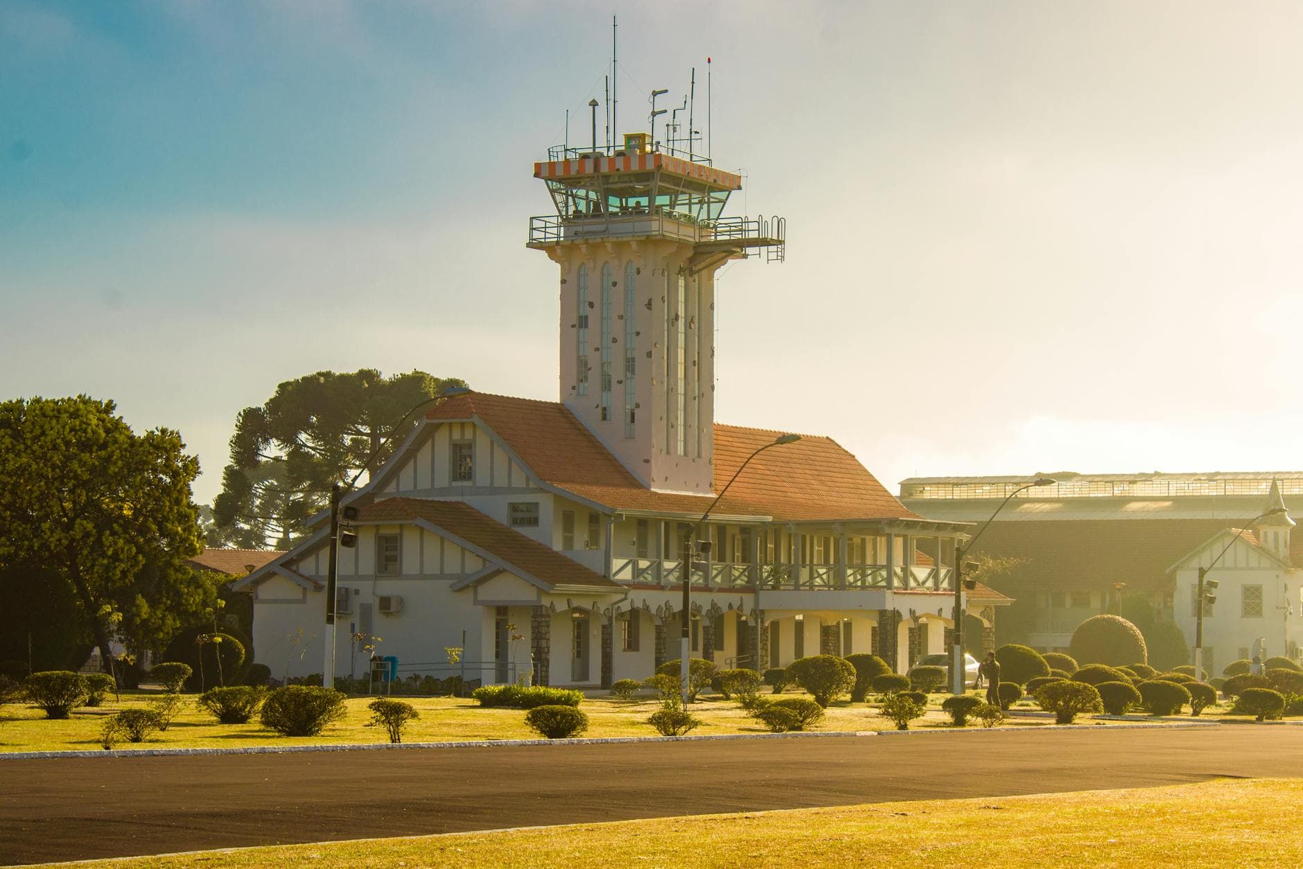 A scenic view of an airport control tower surrounded by sunlight and greenery.