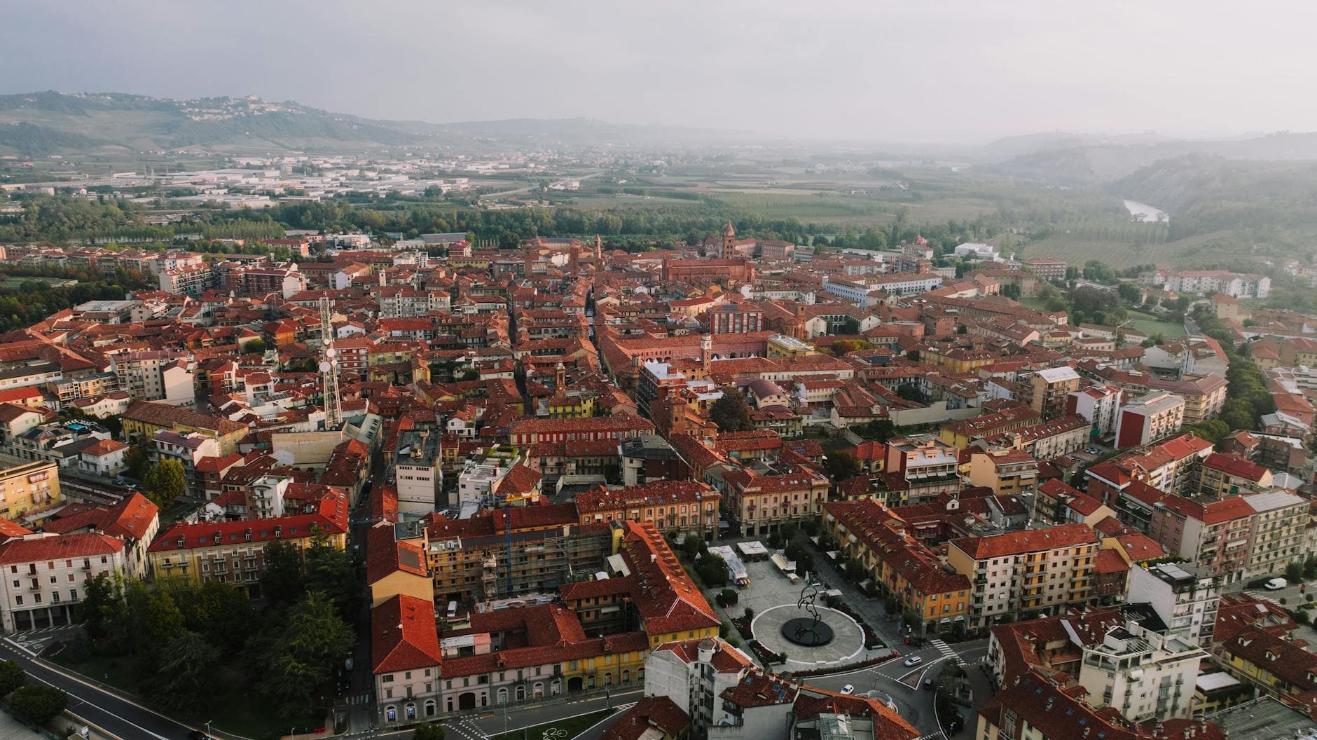 Drone shot capturing the beautiful terracotta rooftops of Alba, Italy, with surrounding countryside.