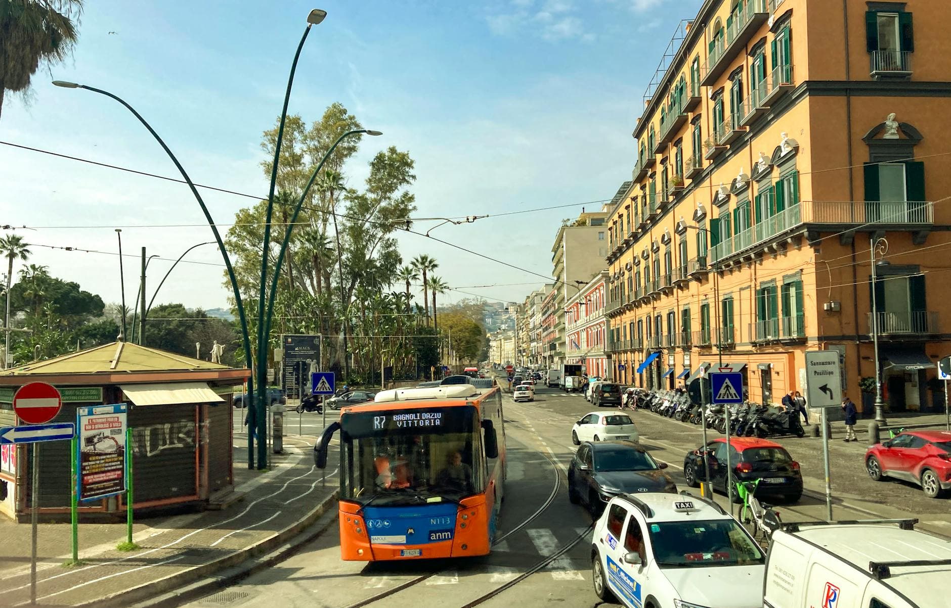 Street view of daily life in Naples with tram, traffic, and historical buildings.