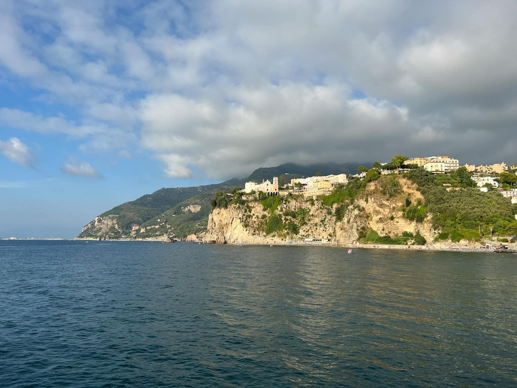 Captivating coastal view of Vico Equense, Campania, Italy, featuring cliffs and blue sea under white clouds.