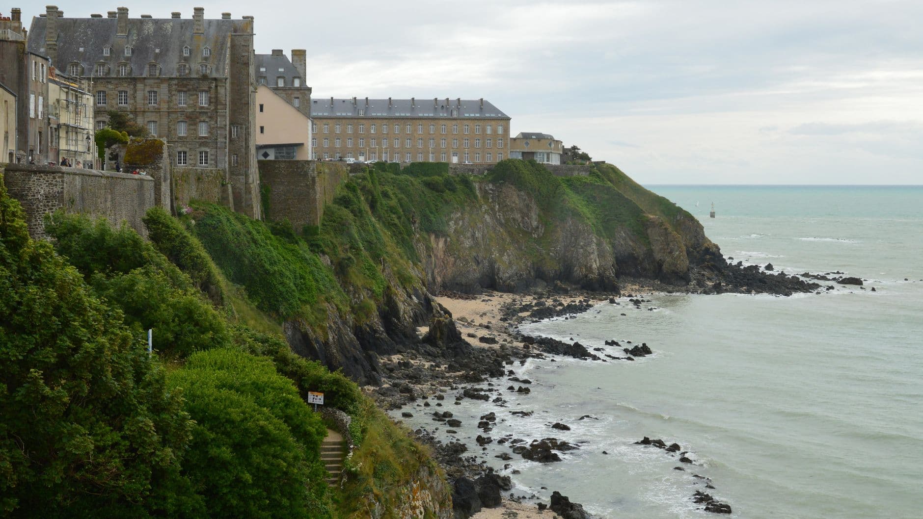 Picturesque view of historic buildings on cliffs in Granville, Normandy with rocky coastline.