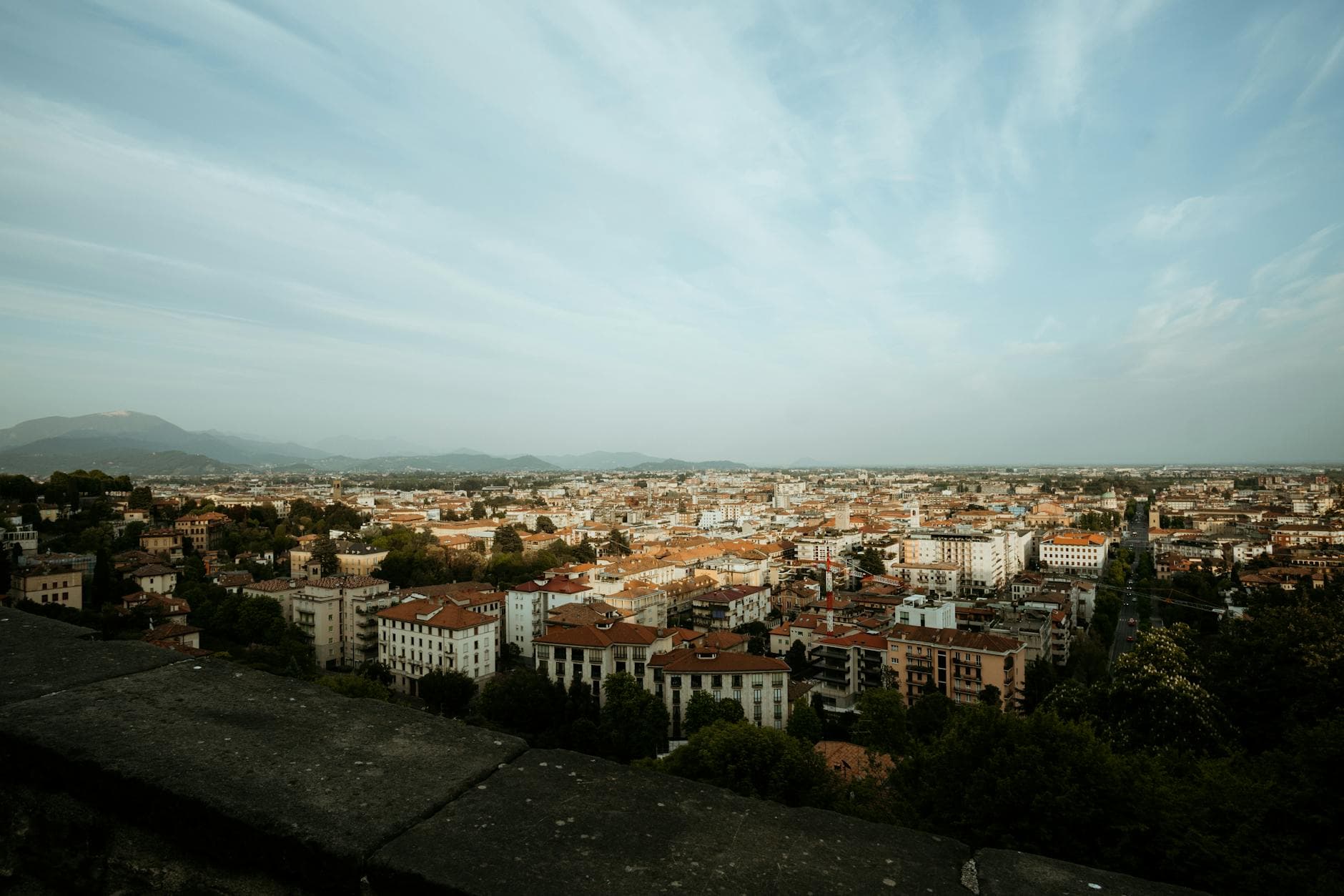 A stunning aerial view of an Italian city with historic architecture and mountainous backdrop.