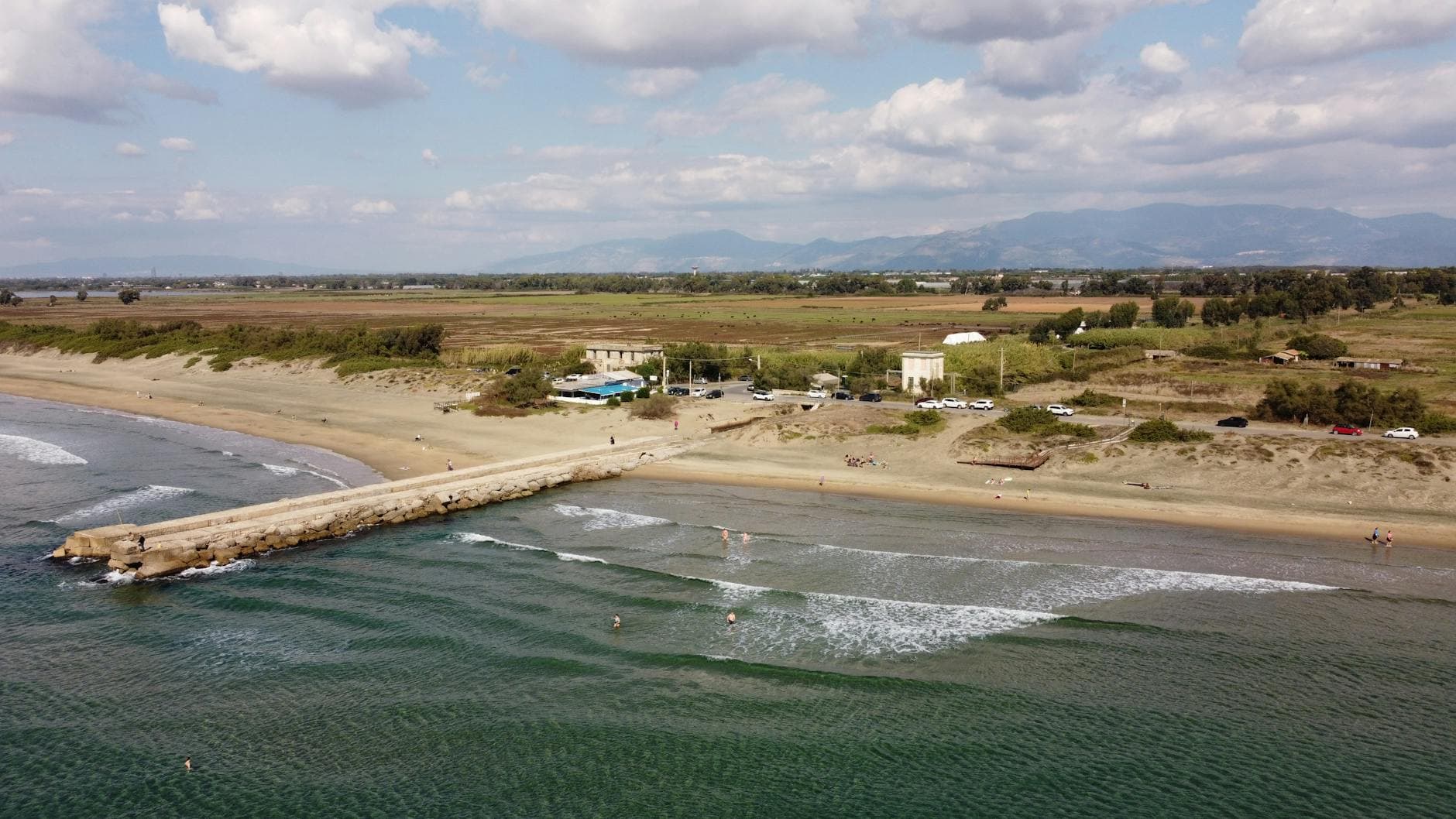 Scenic aerial view of the beach and pier in Anzio, Lazio, Italy under a cloudy sky.