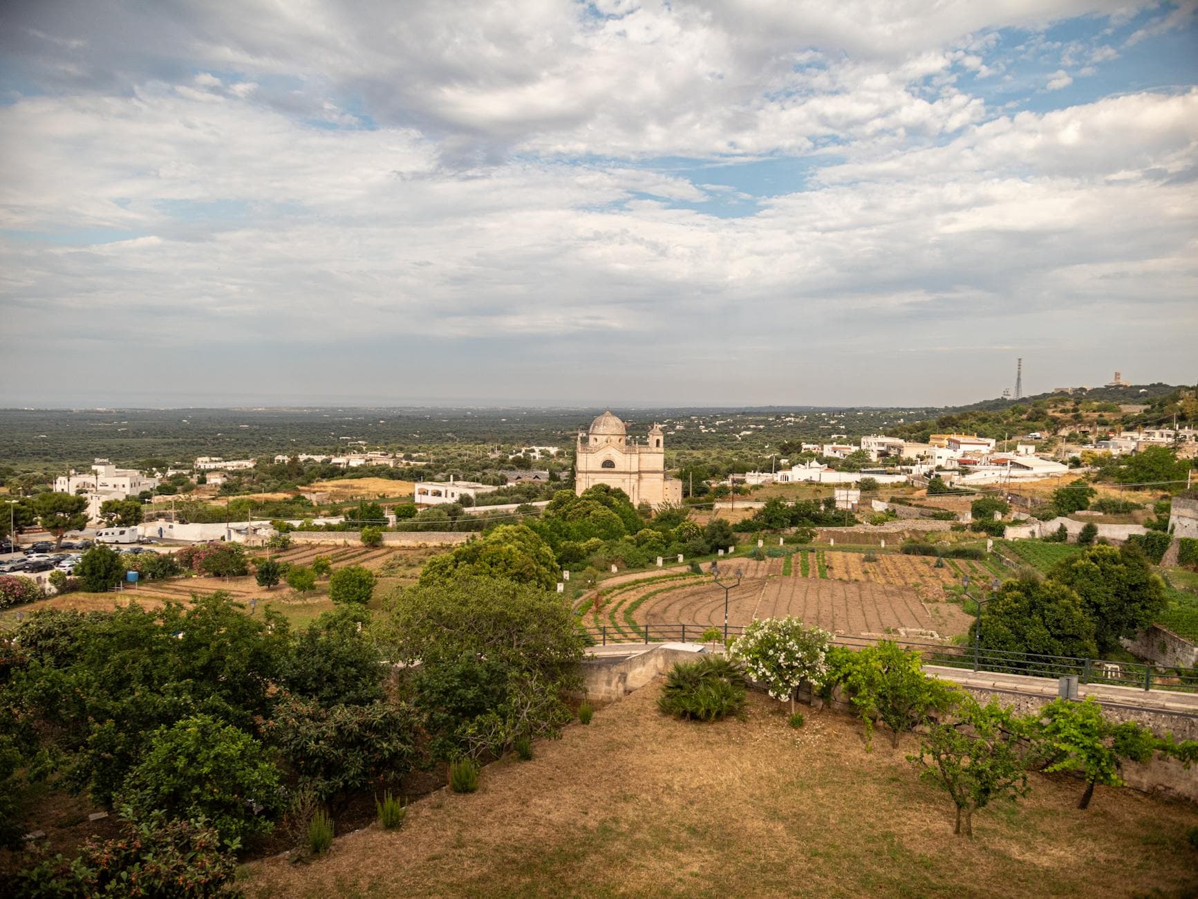 A scenic aerial shot of Ostuni, Italy showcasing the countryside and an historic church.