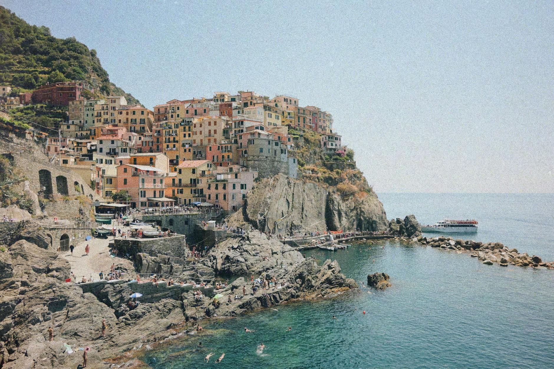 Breathtaking coastal view of Manarola's colorful architecture and rocky shoreline in Cinque Terre, Italy.