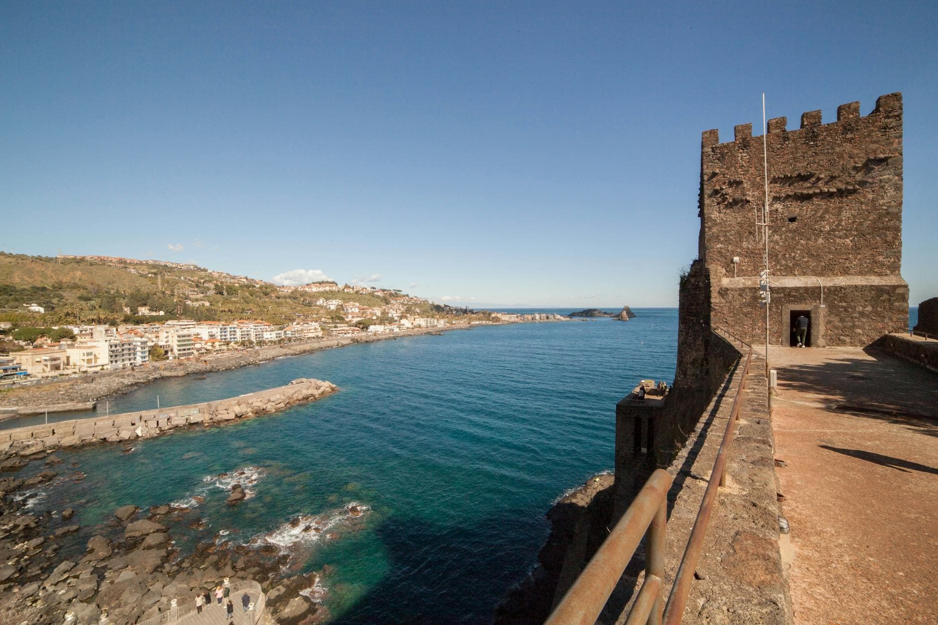 Stunning view of Aci Castello Castle and coastline in Sicily, Italy with clear blue waters.