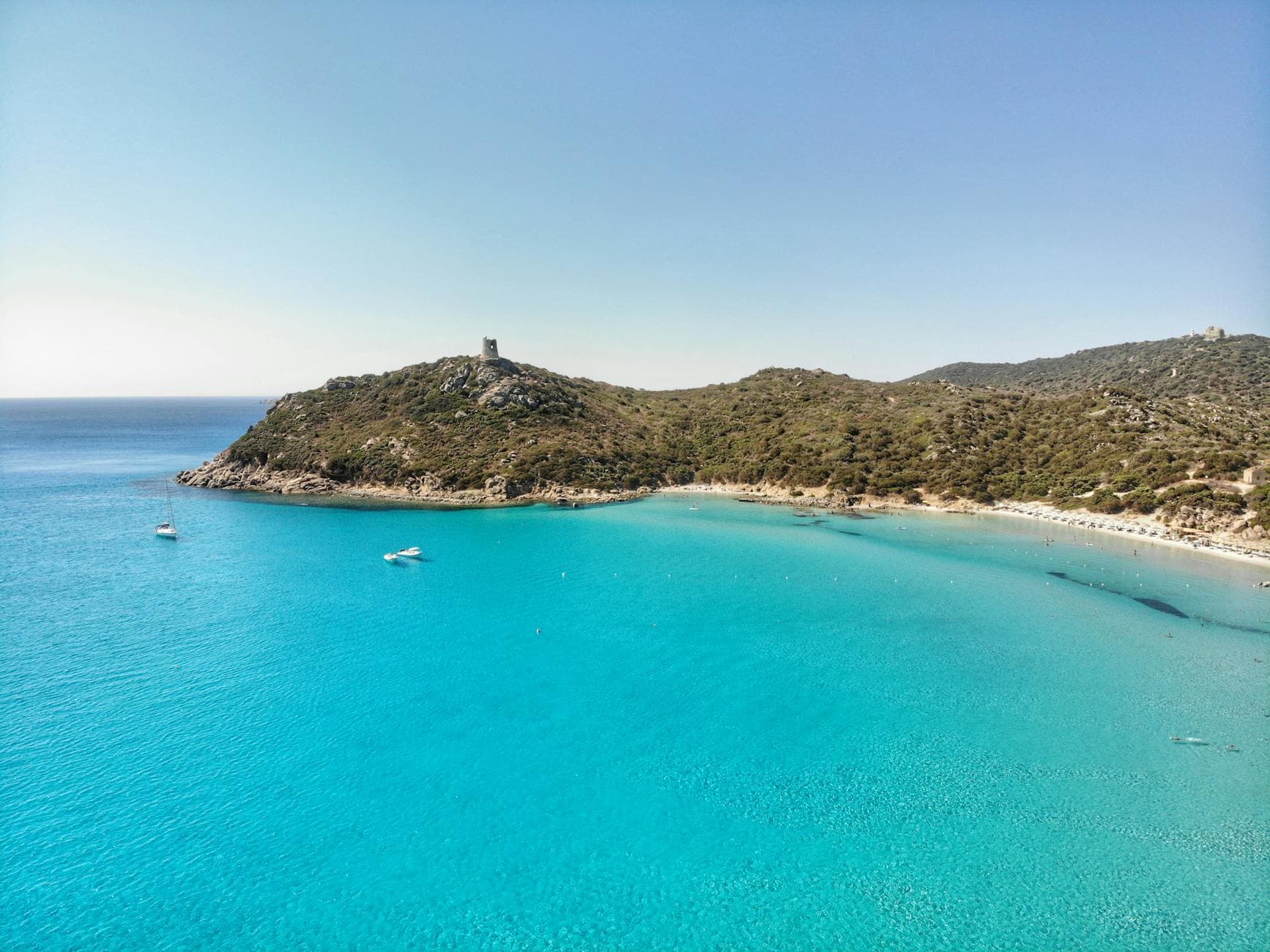 A scenic aerial view of the Porto Giunco Tower and turquoise waters in Villasimius, Sardinia, Italy.