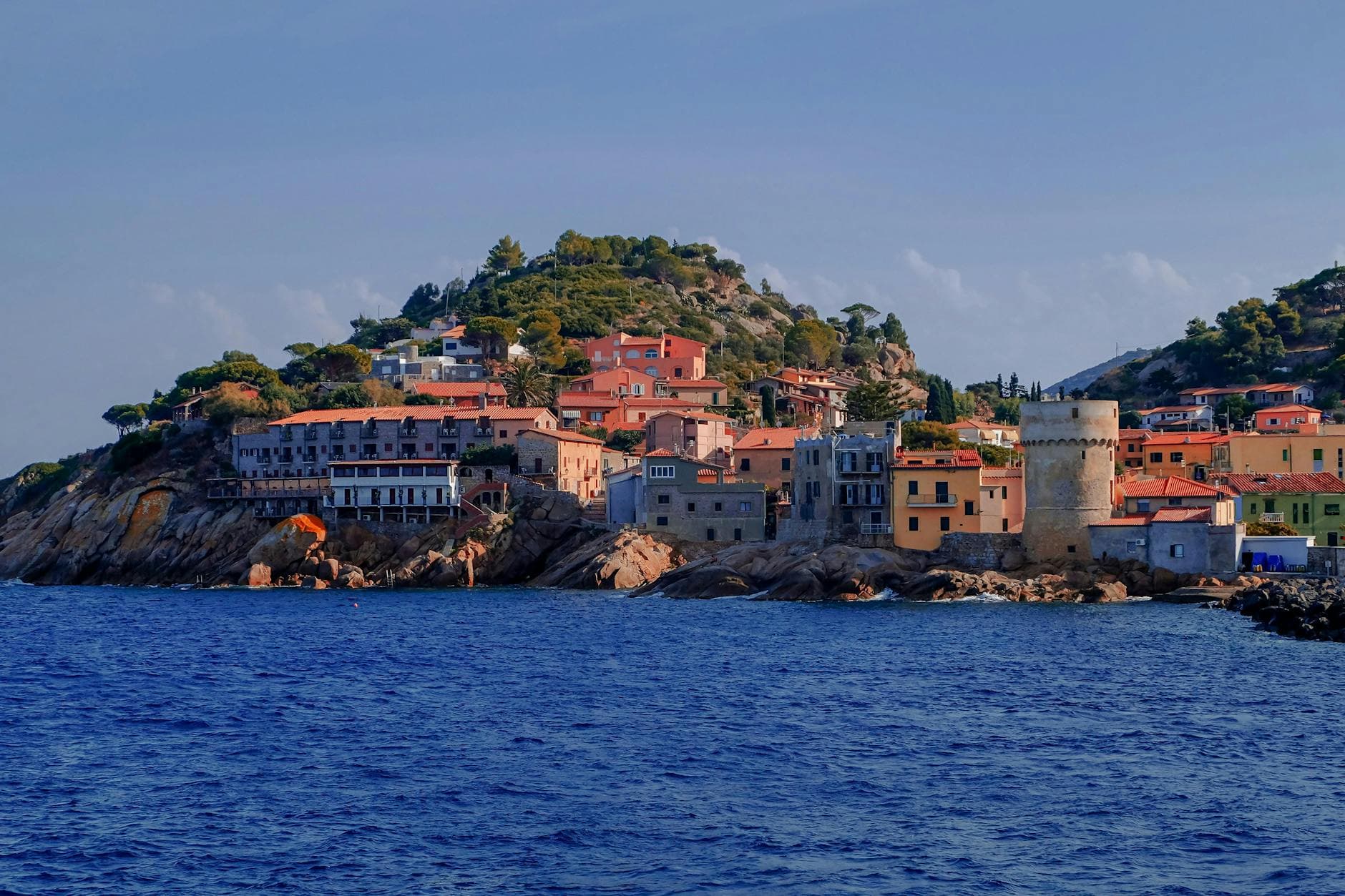Vibrant coastal buildings with a historic tower on a sunny day in Tuscany, Italy.