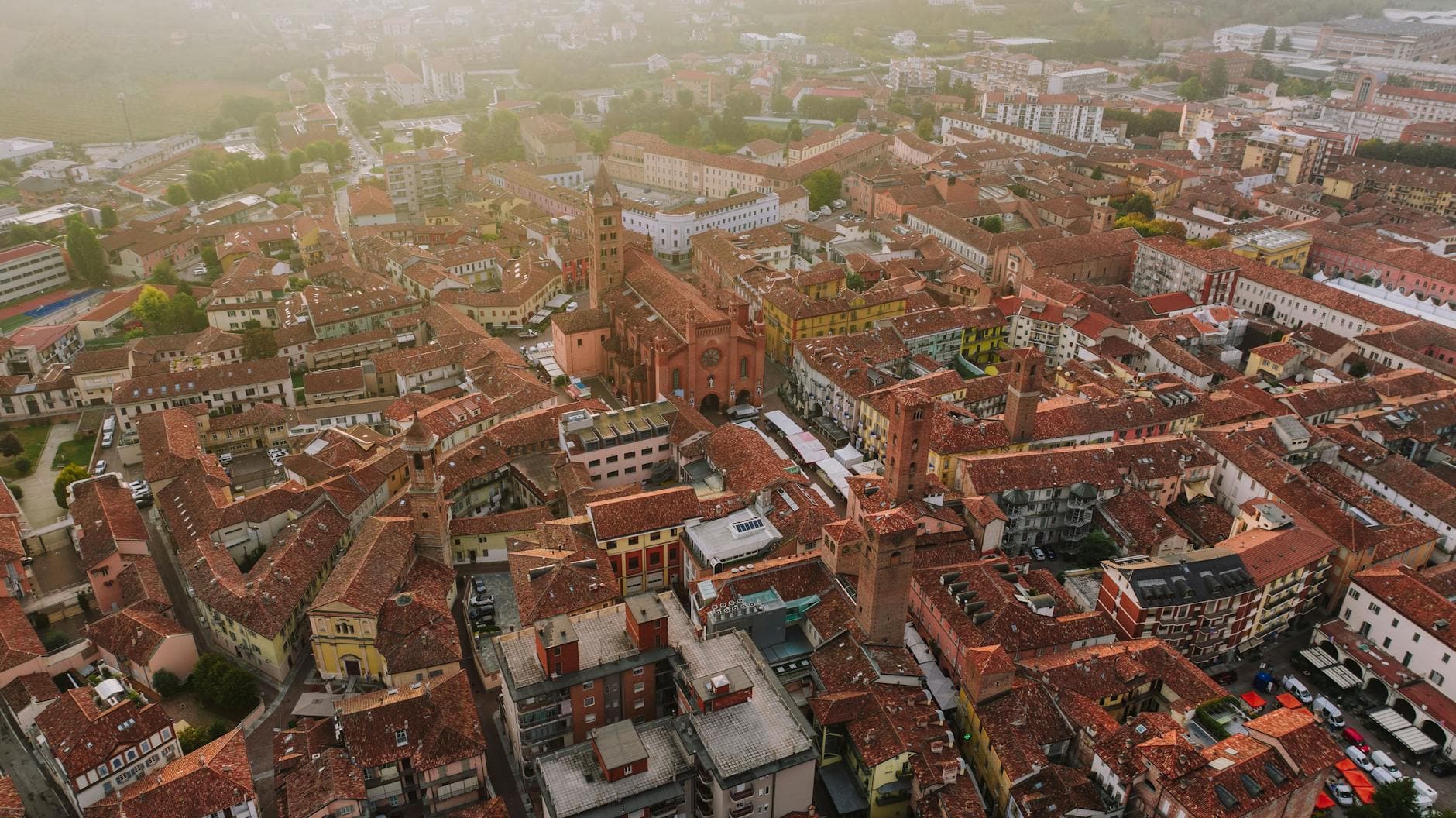 Captivating aerial view of Alba, Italy highlighting its historic buildings and vibrant townscape during sunset.