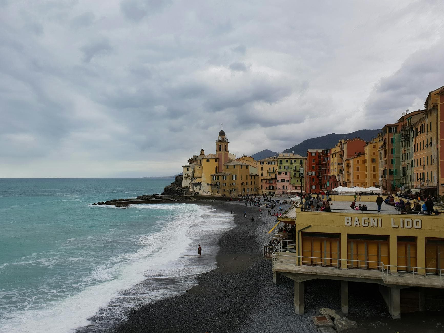 Picturesque coastline of Camogli, Italy with colorful buildings and dramatic clouds.