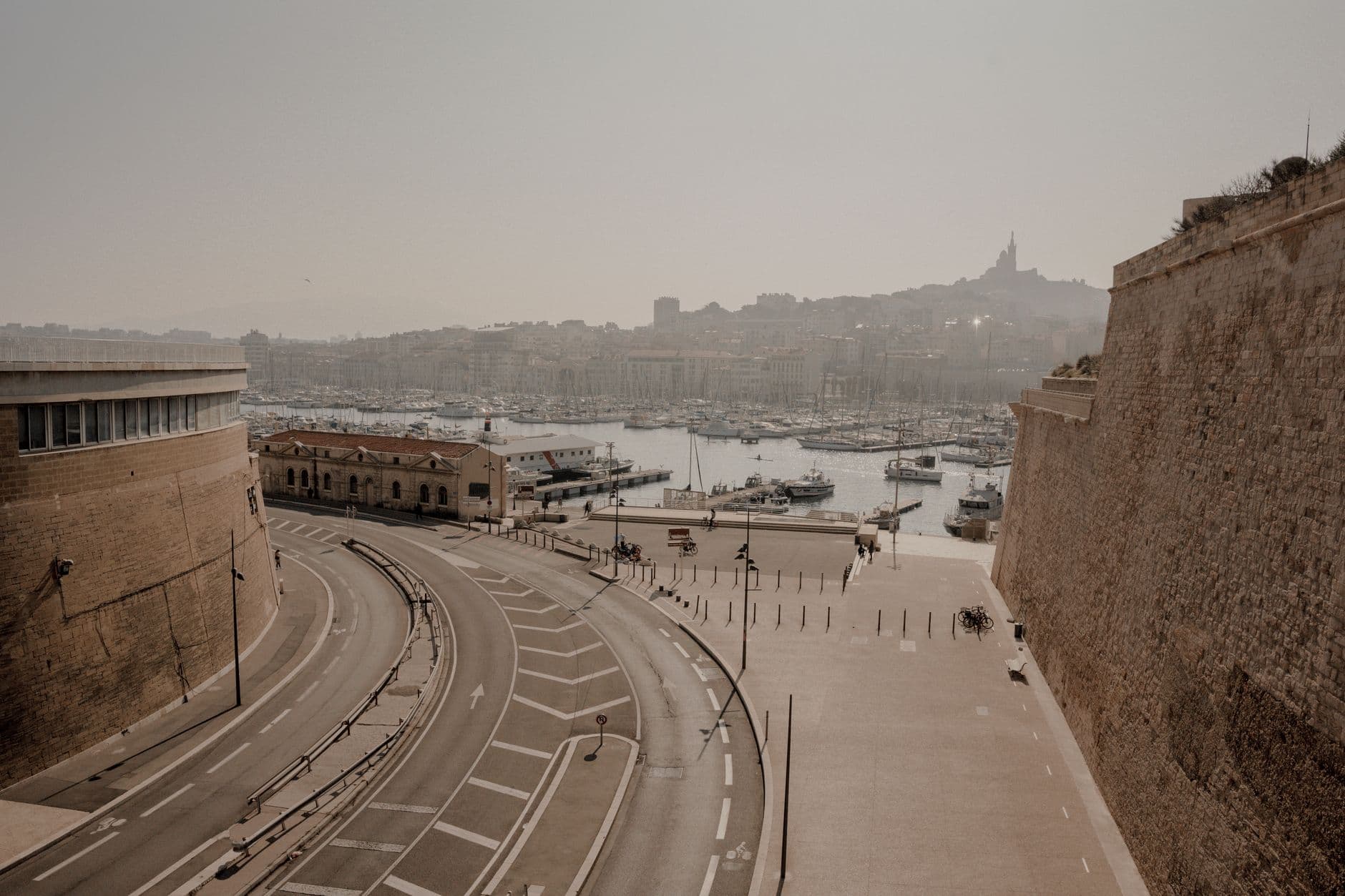 A tranquil view of Marseille's harbor, featuring winding roads, historical architecture, and a serene waterfront.