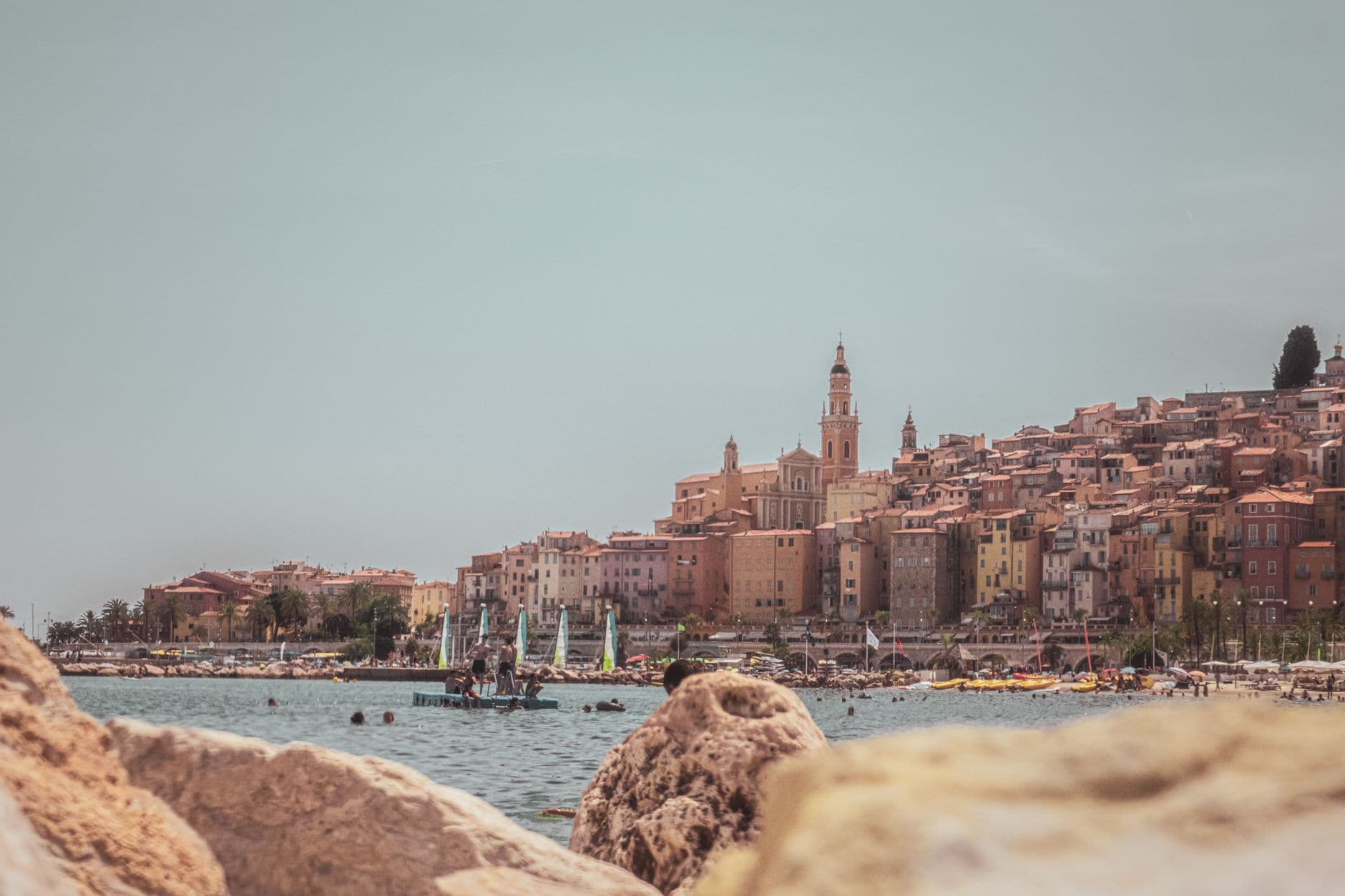 Scenic coastline of Menton, France, featuring colorful historic buildings and the Mediterranean Sea in a serene summer setting.