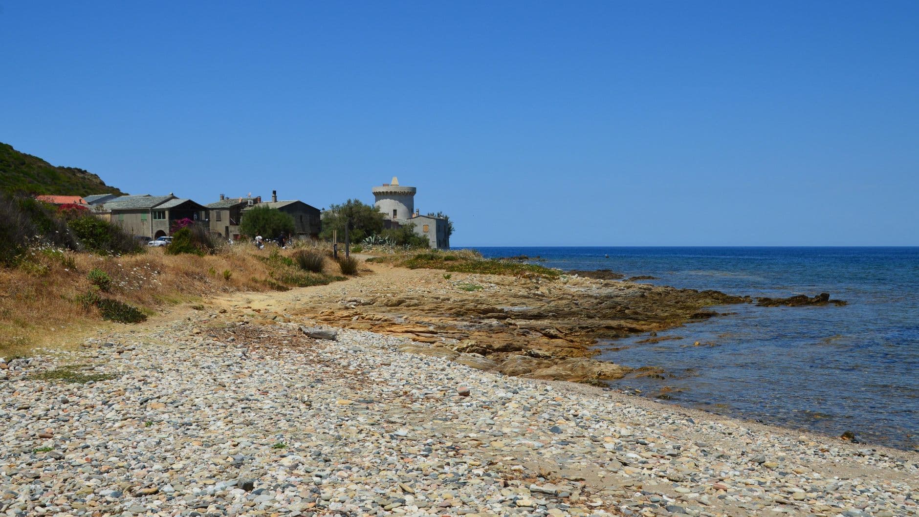 Beautiful rocky beach with a historic tower in Ersa, Corsica, perfect for travel and nature lovers.