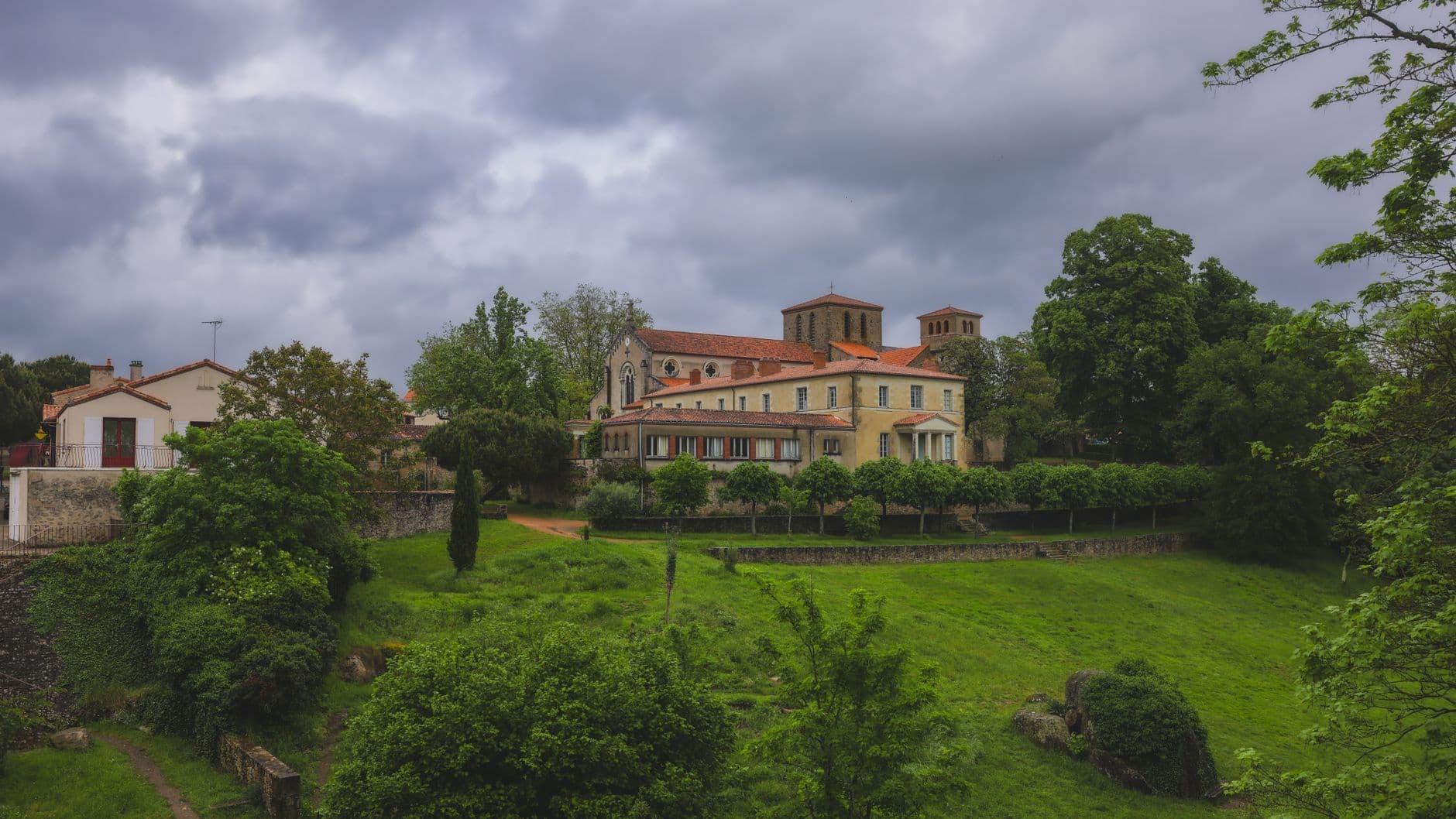 Scenic view of a historic church surrounded by lush greenery in Clisson, France.