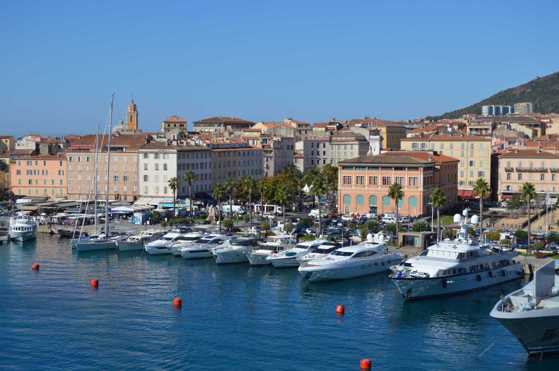 Stunning view of Ajaccio's harbor in Corsica, featuring white yachts and historic town buildings along the coastline.