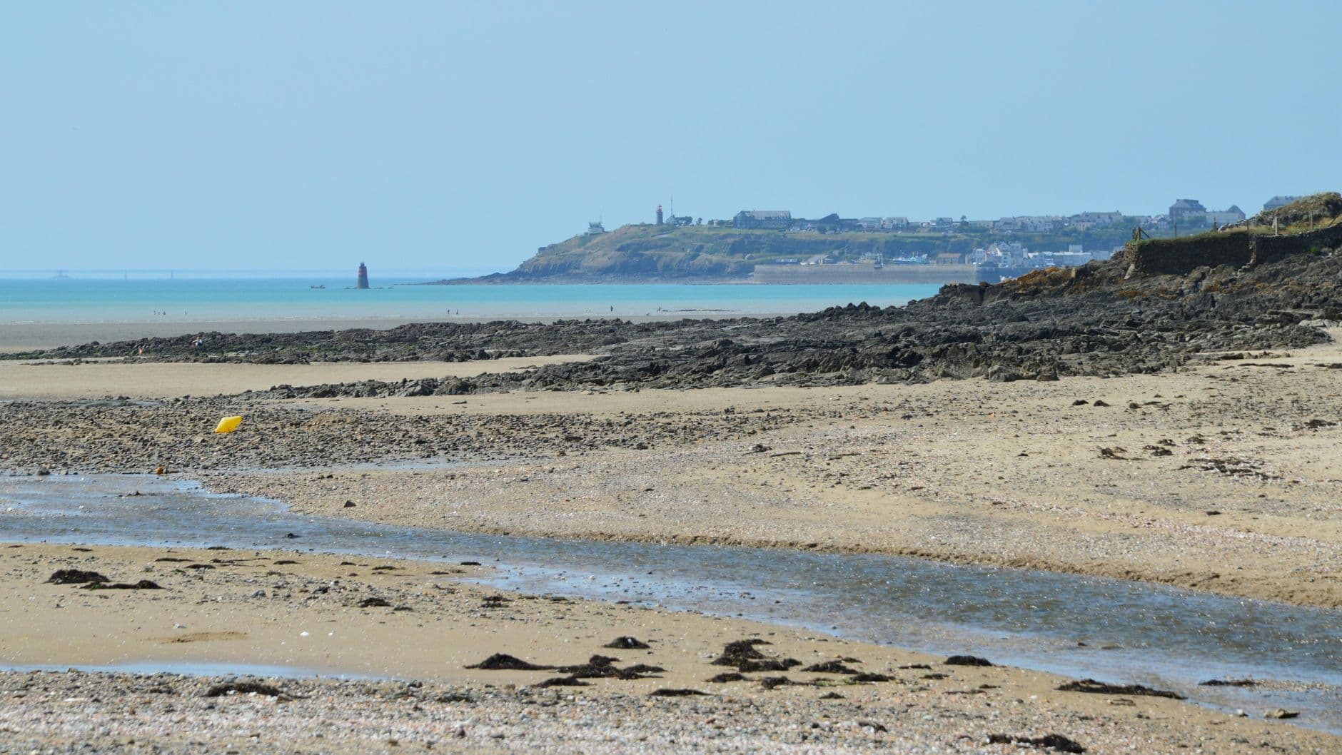 Explore the serene coastal landscape of Saint-Pair-sur-Mer with sandy beaches and distant views of the town.