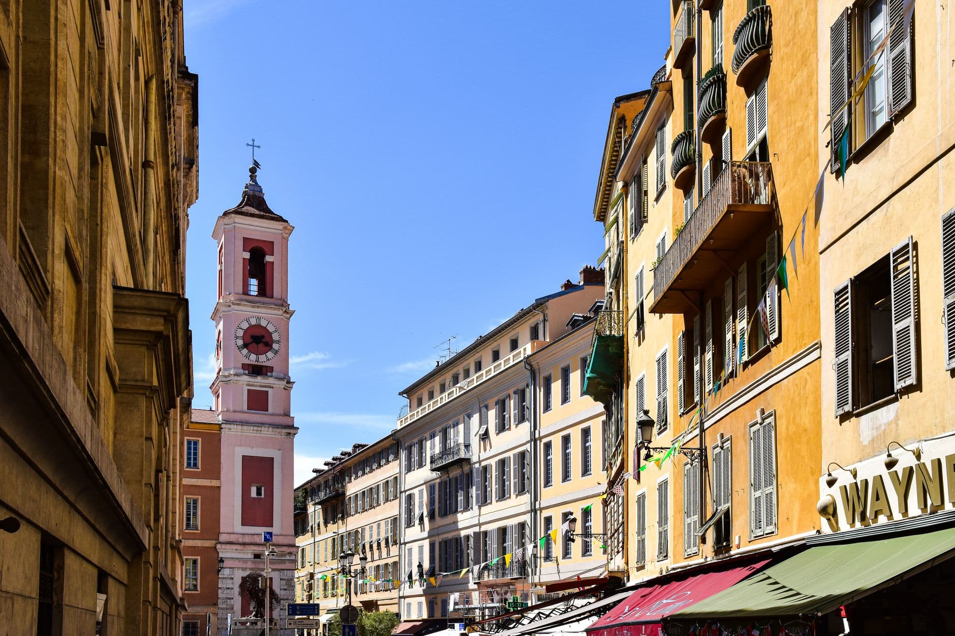 Colorful buildings and a bell tower under a clear sky in Old Nice, France.