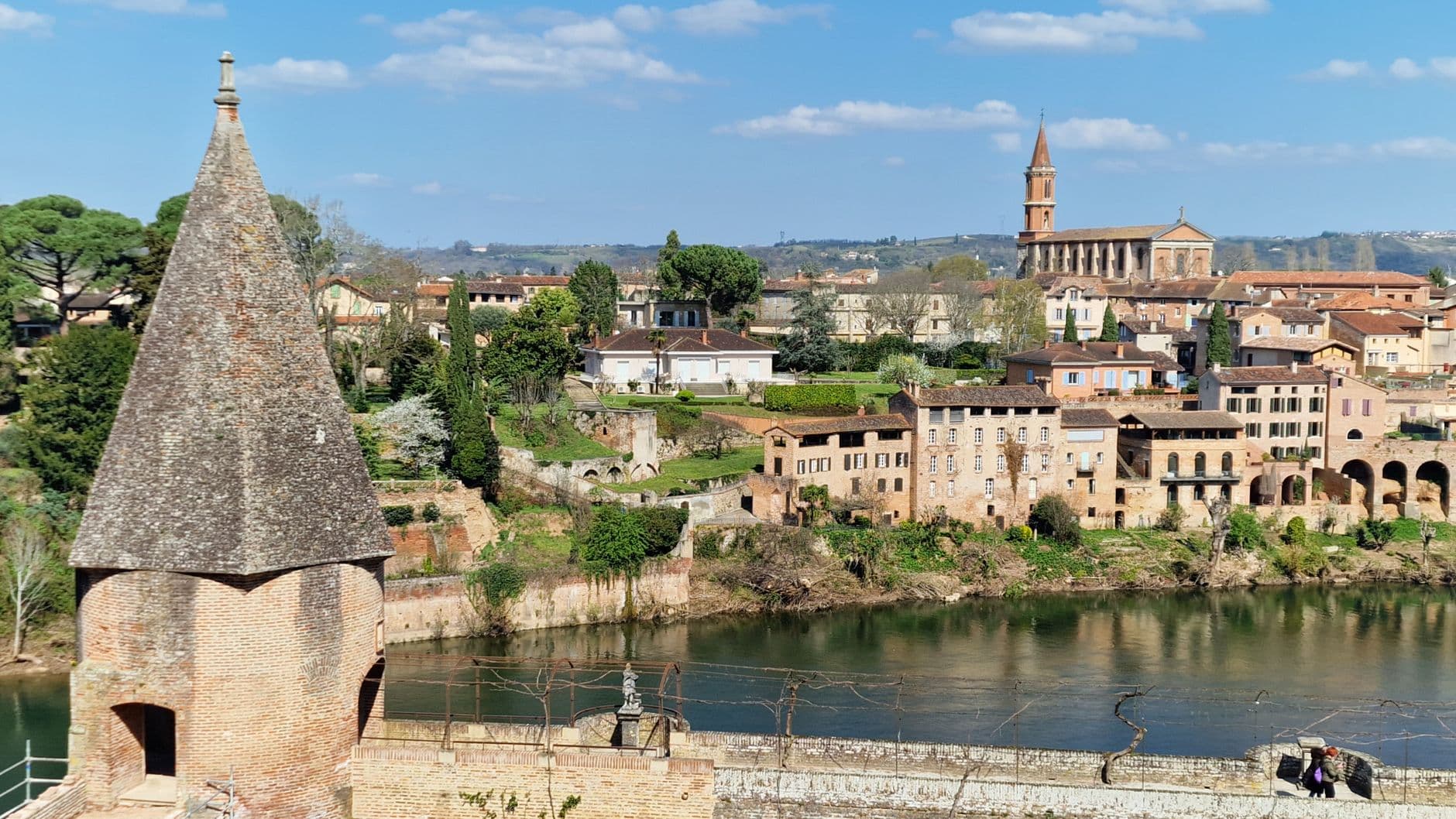 Charming riverside town in France with historical architecture and a church tower.