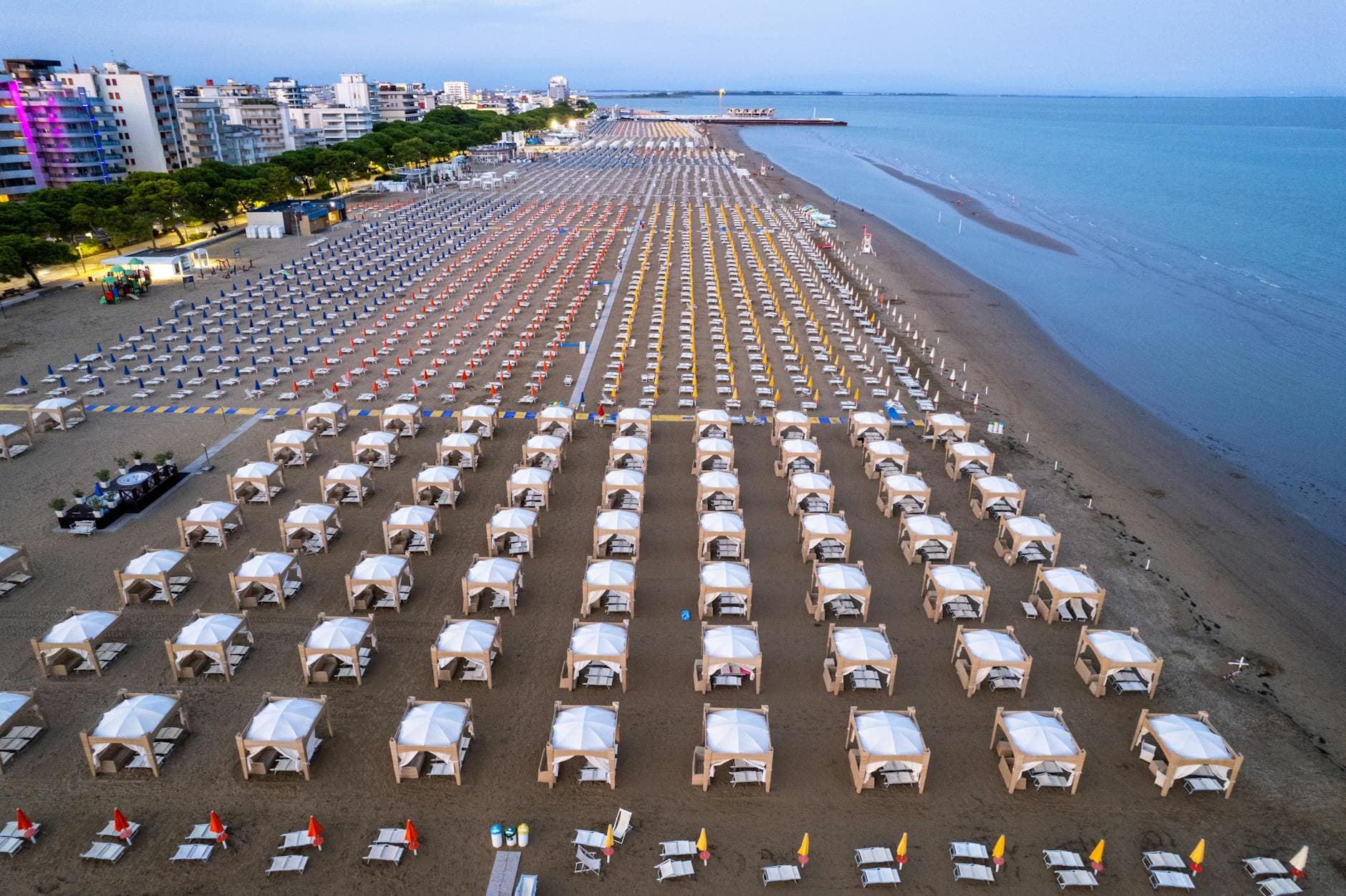 Aerial shot of organized beach cabanas in Lignano Sabbiadoro, Italy at evening.