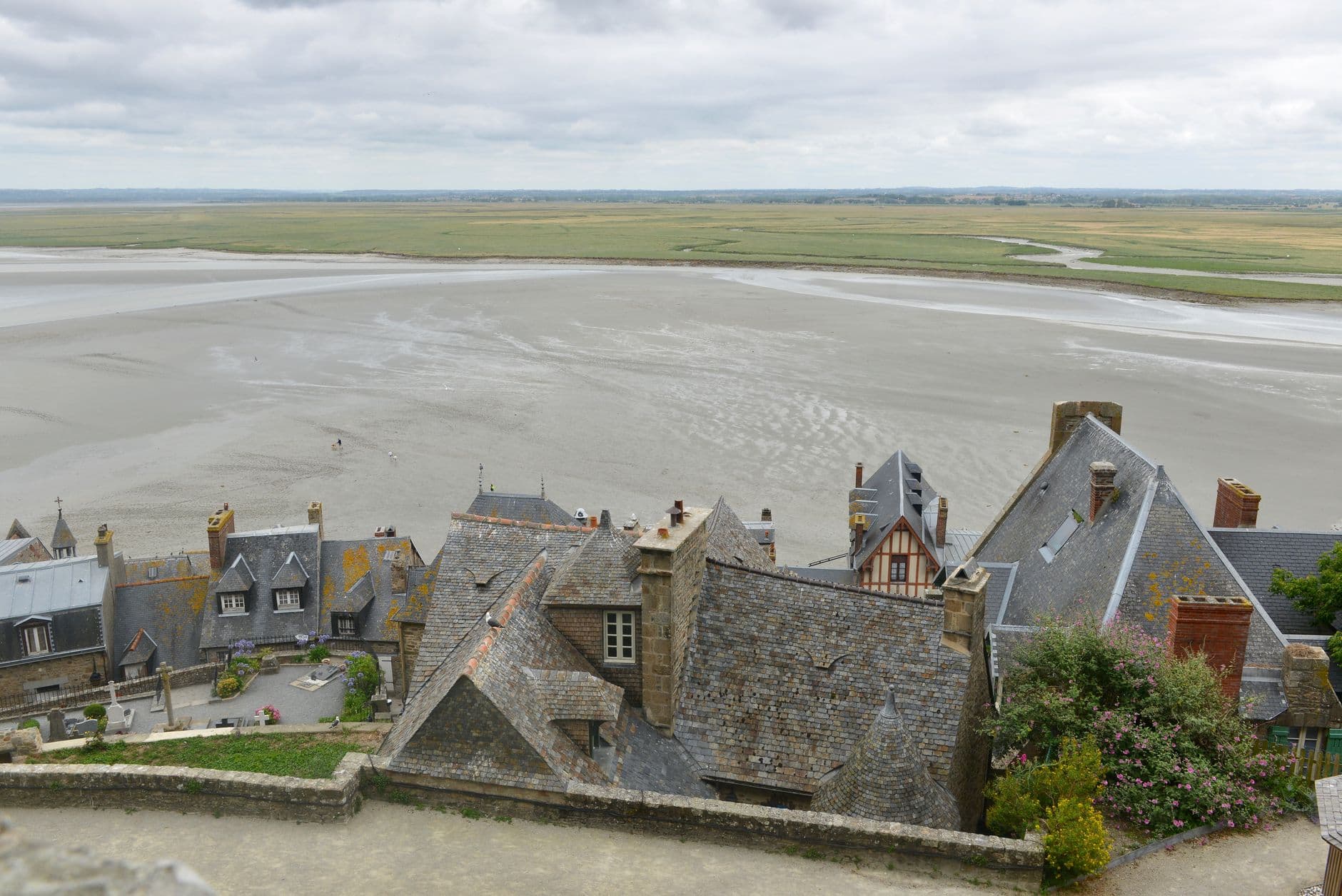 Aerial view of historical rooftops at Le Mont-Saint-Michel with scenic landscape and bay.
