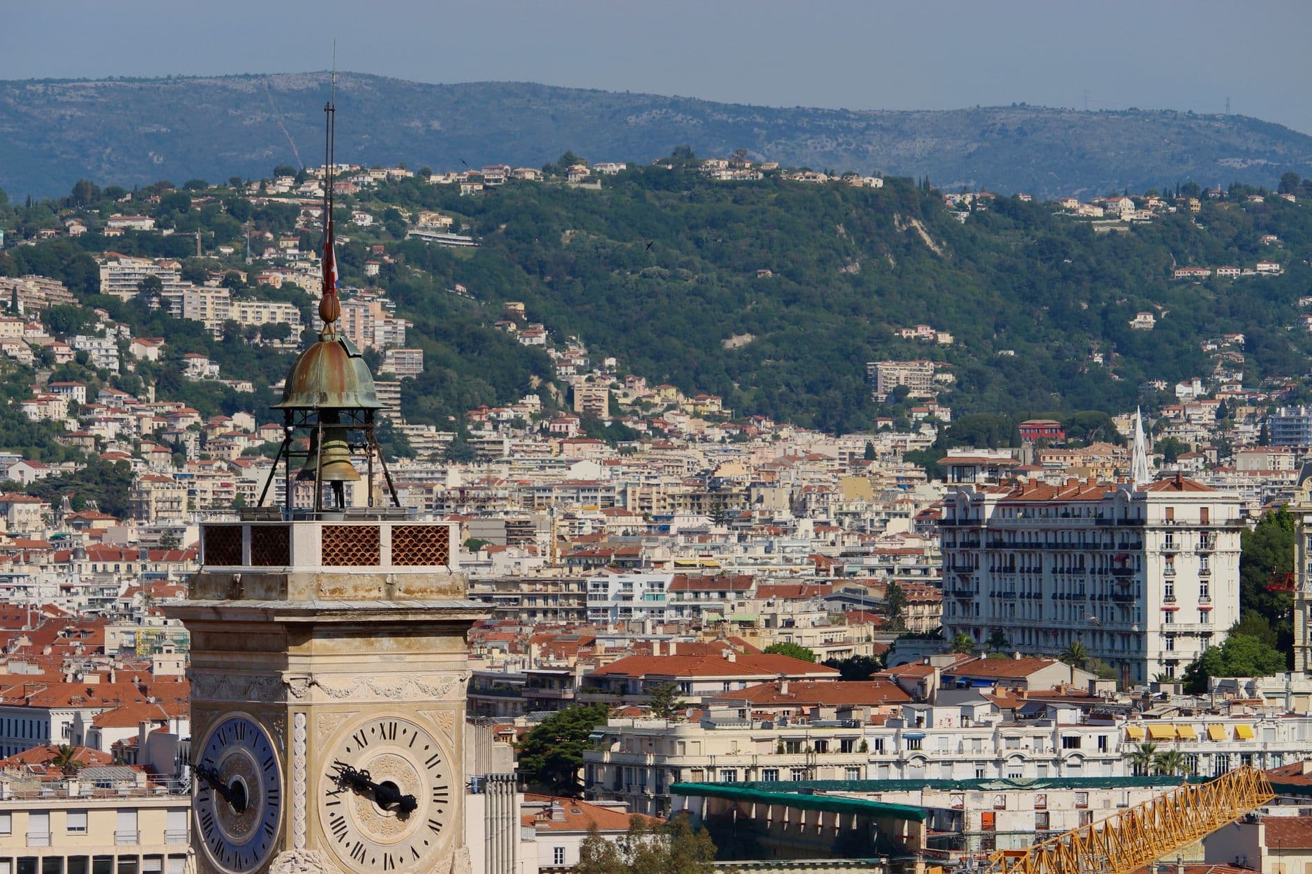 A stunning view of a historic clock tower with the cityscape of Nice, France in the background.