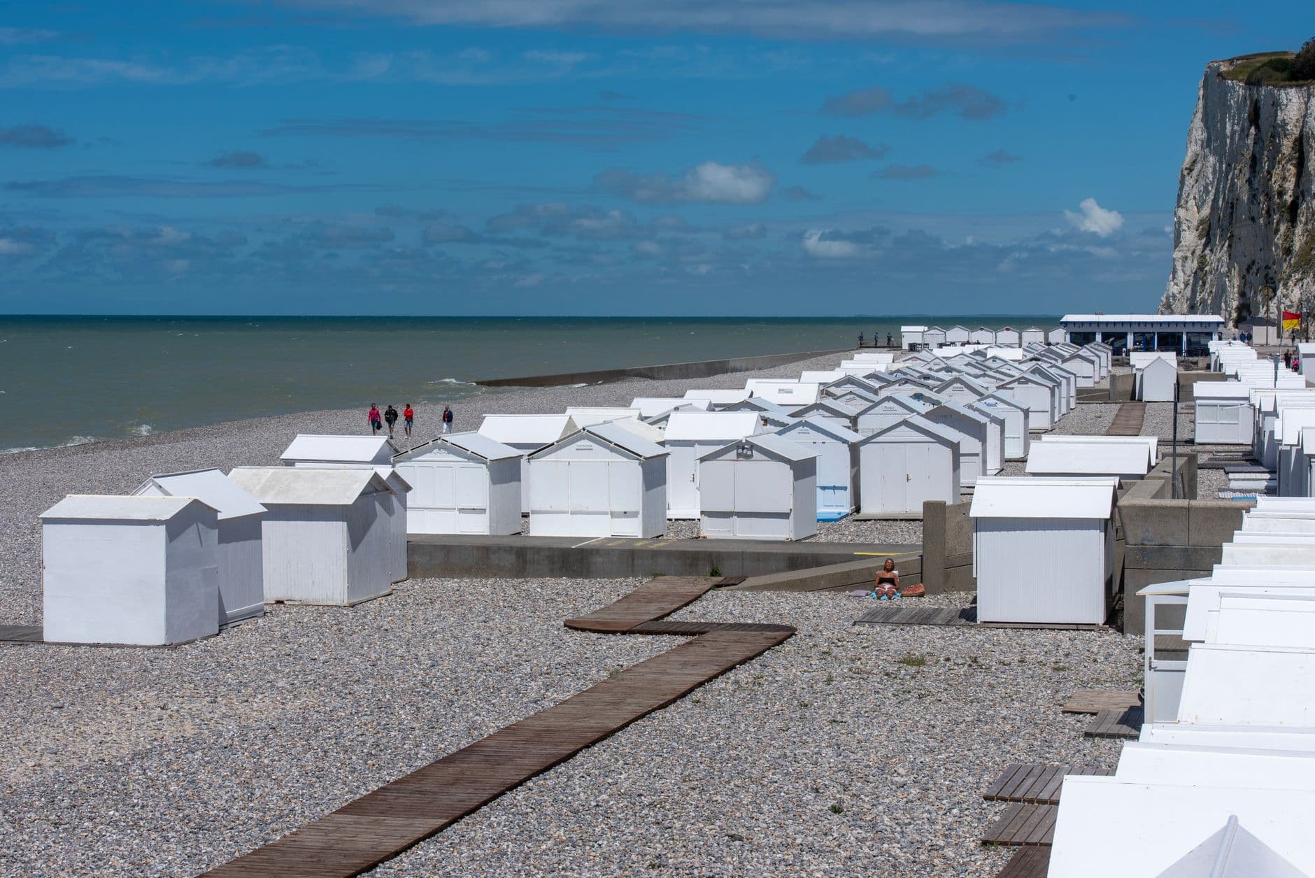 Scenic view of white beach huts on a pebble beach in Mers-les-Bains, France.