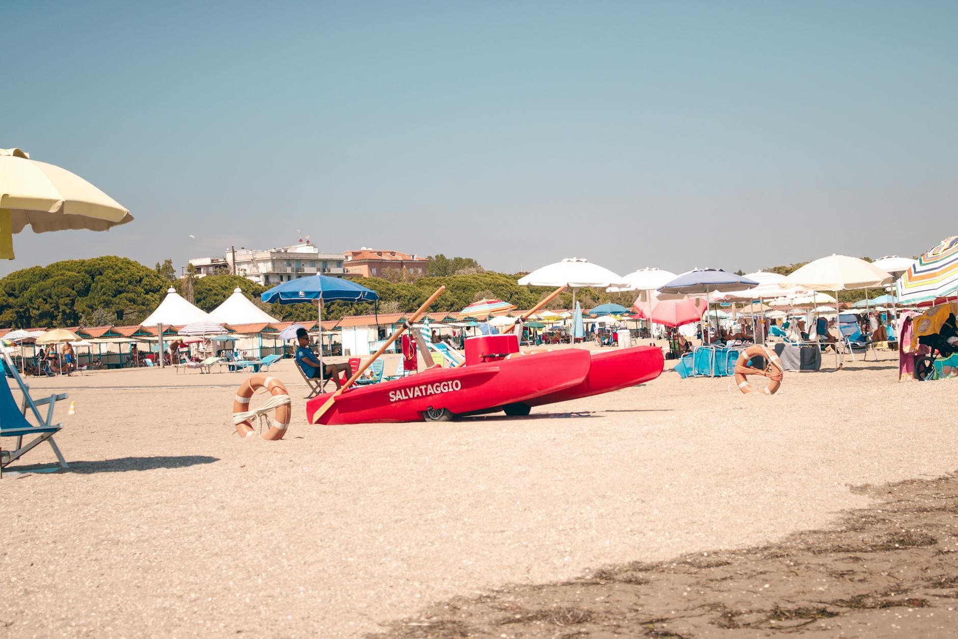 Scenic view of Venedik, Italy's sandy beach with vibrant umbrellas and lifeguard boat.