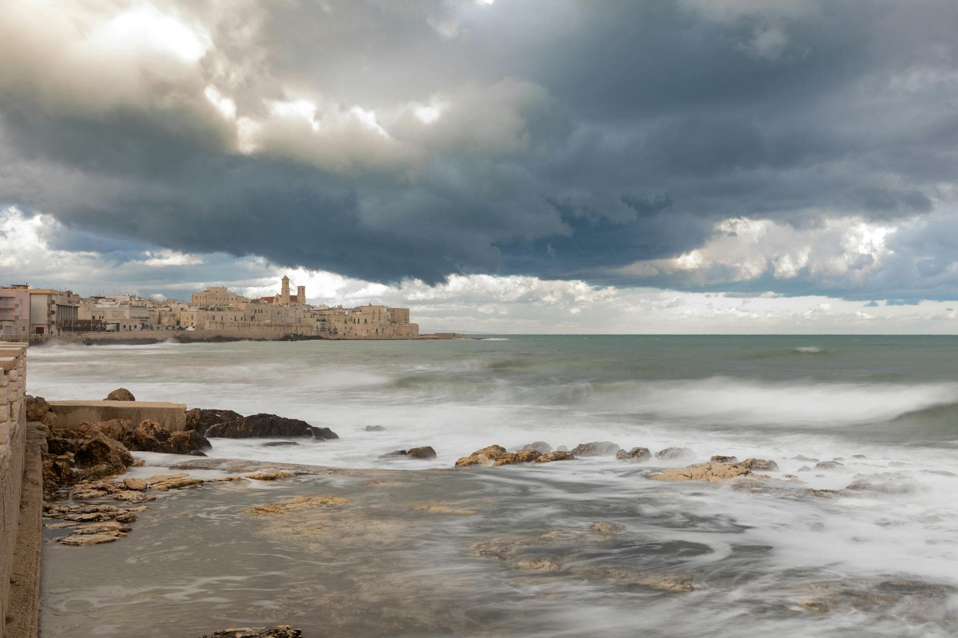 A stunning view of Vieste's coastline under dramatic clouds and serene ocean waves.