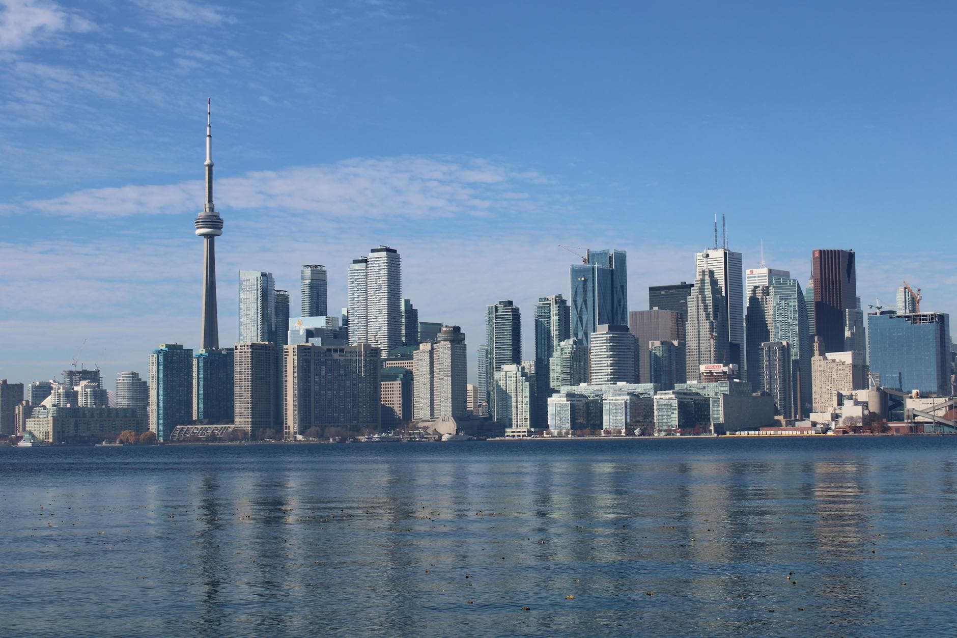 Stunning view of Toronto skyline with CN Tower from waterfront under clear blue sky.