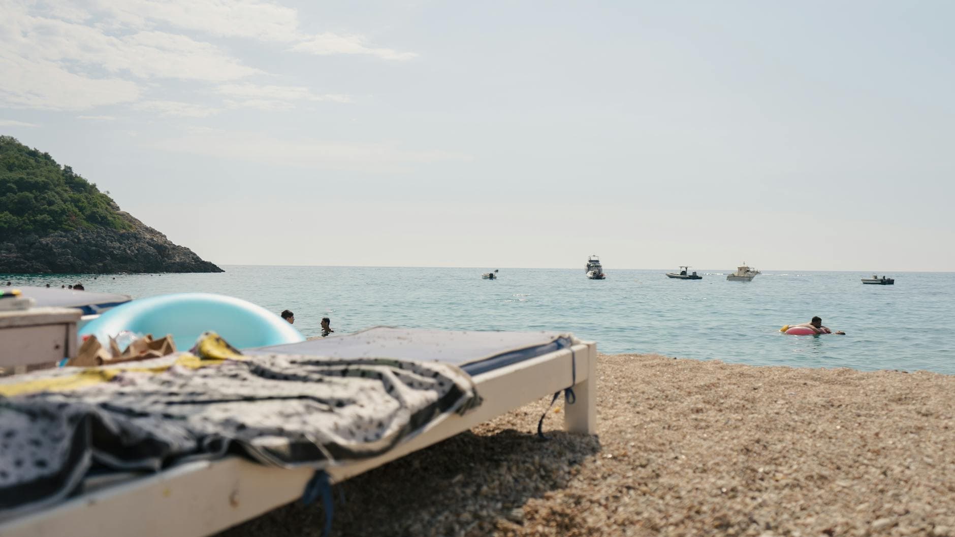 Relaxing beach scene in Vlorë County, Albania with boats and sunbathers.