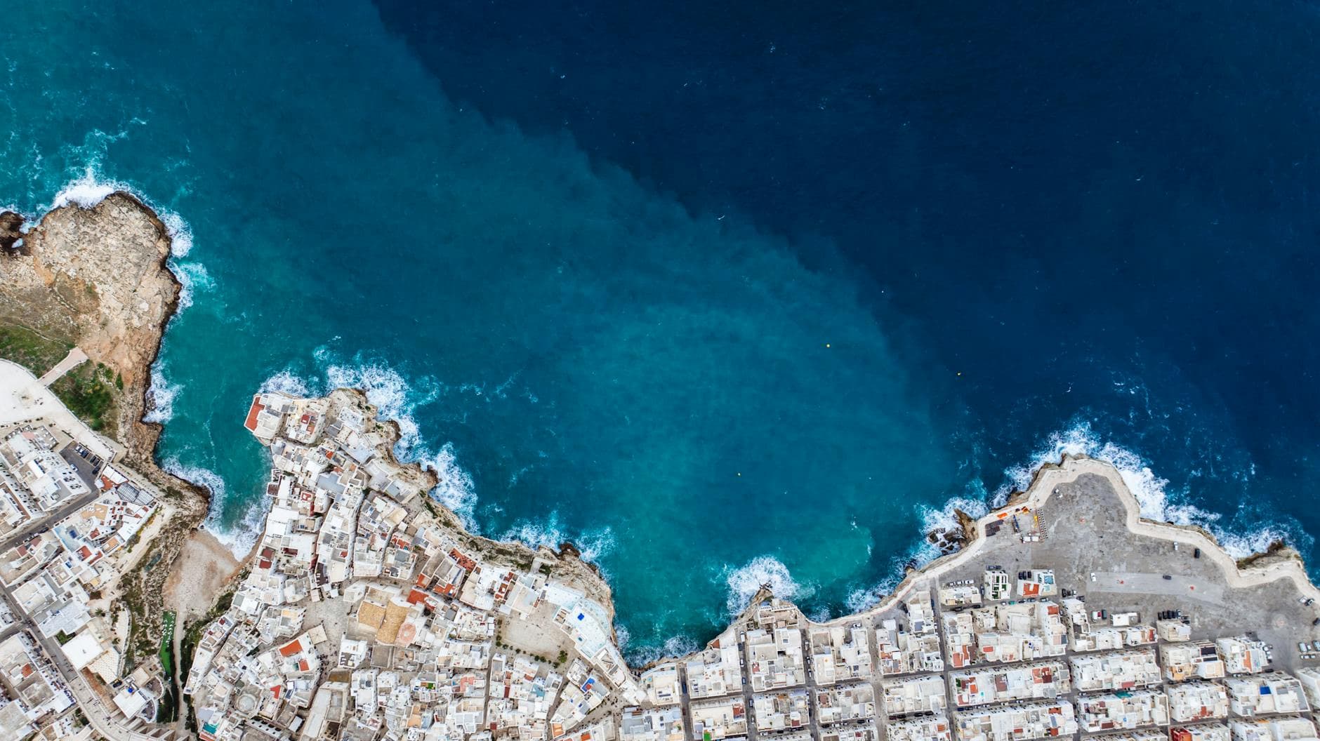 Breathtaking aerial shot of Polignano a Mare, Italy's scenic blue coastline and urban landscape.