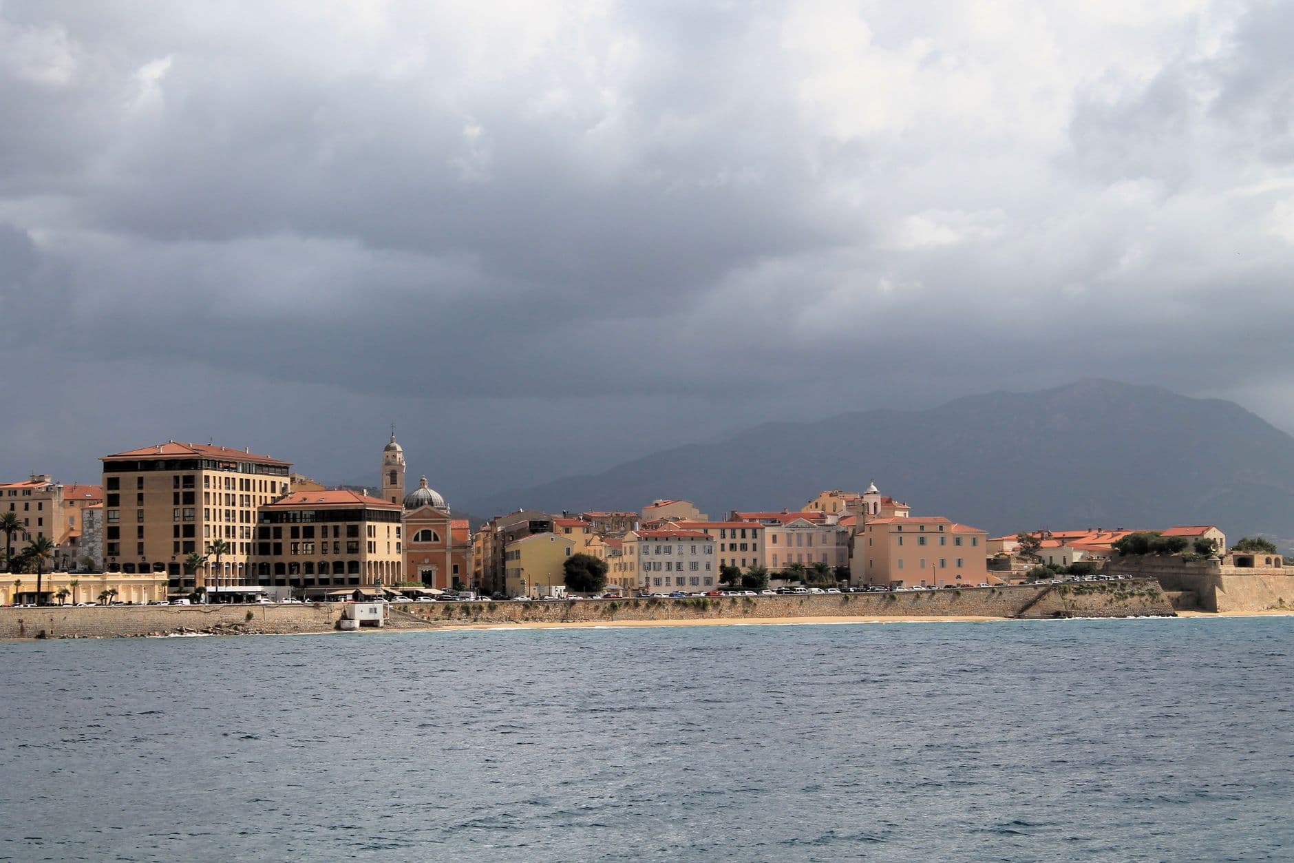 Scenic view of a coastal town with historic buildings and cloudy sky, ideal for travel and architecture themes.
