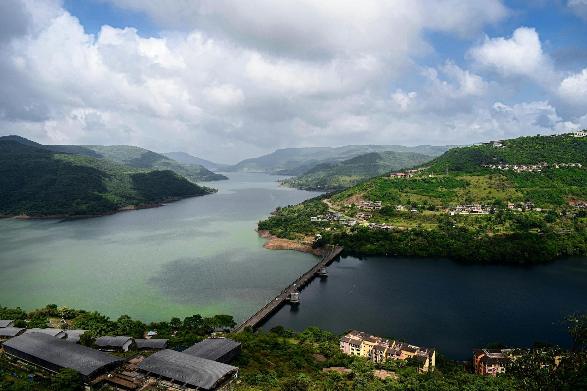 Aerial view showcasing a picturesque bridge crossing a serene river amidst lush green hills.