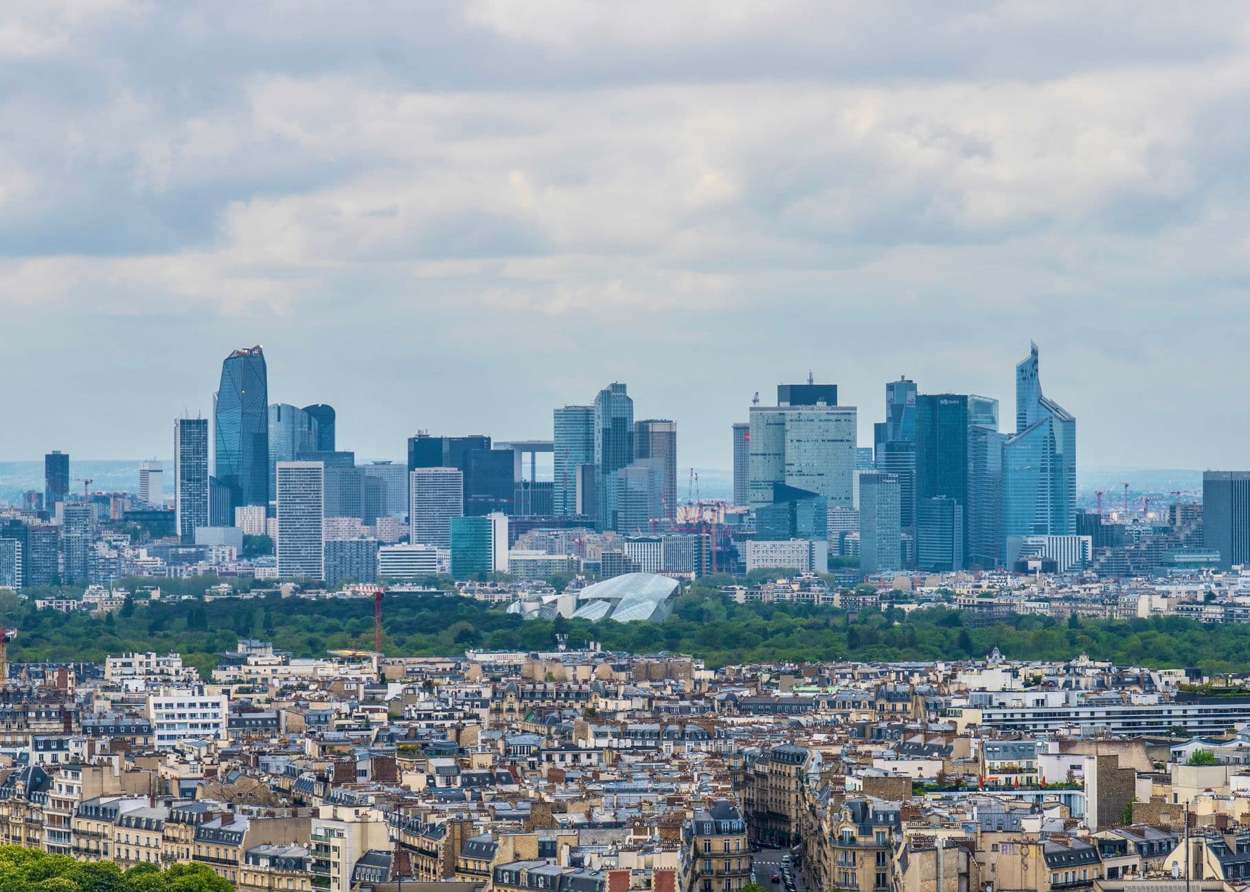 Aerial view of Paris showcasing the modern La Défense skyline with towering skyscrapers.