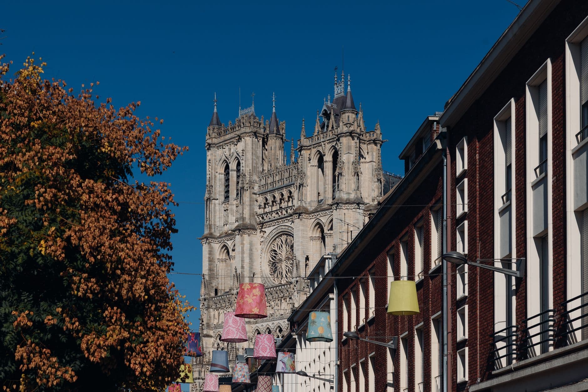 View of Amiens Cathedral with colorful street decorations on a sunny day.