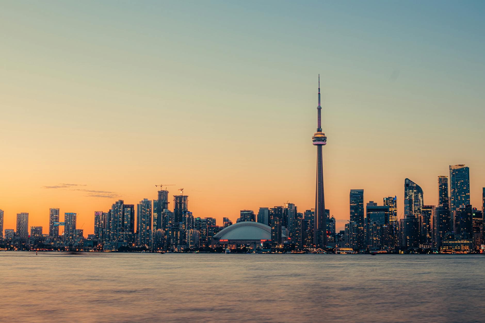 Stunning view of Toronto's skyline at sunset, highlighting the CN Tower and Lake Ontario waterfront.
