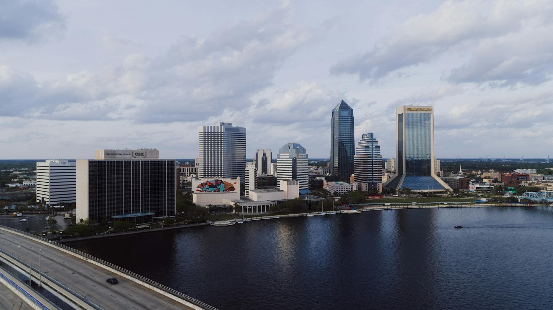 A stunning aerial view of Jacksonville's modern skyline by the river under a cloudy sky.