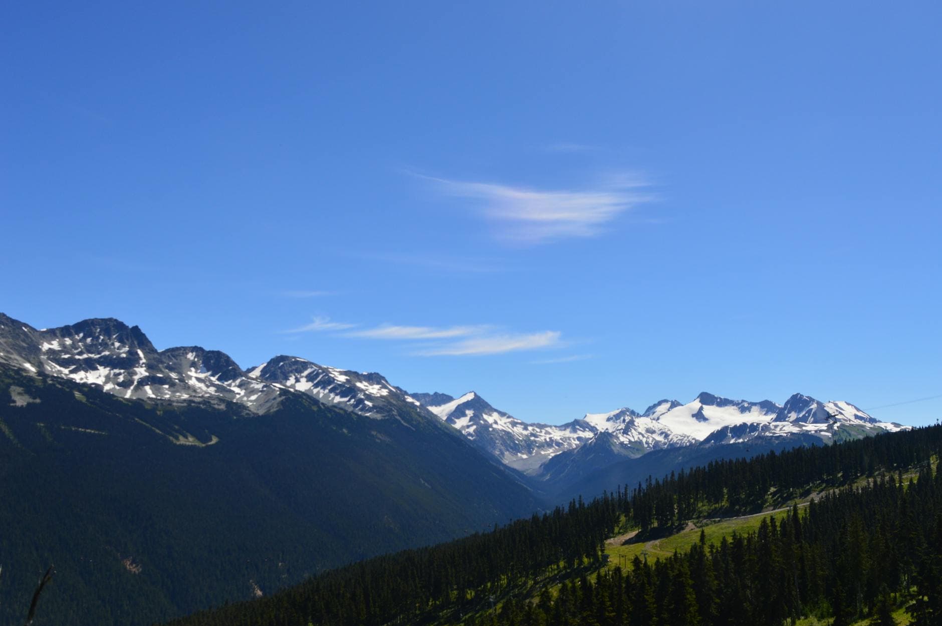 Panoramic view of snow-capped mountains and blue sky in Whistler, Canada.