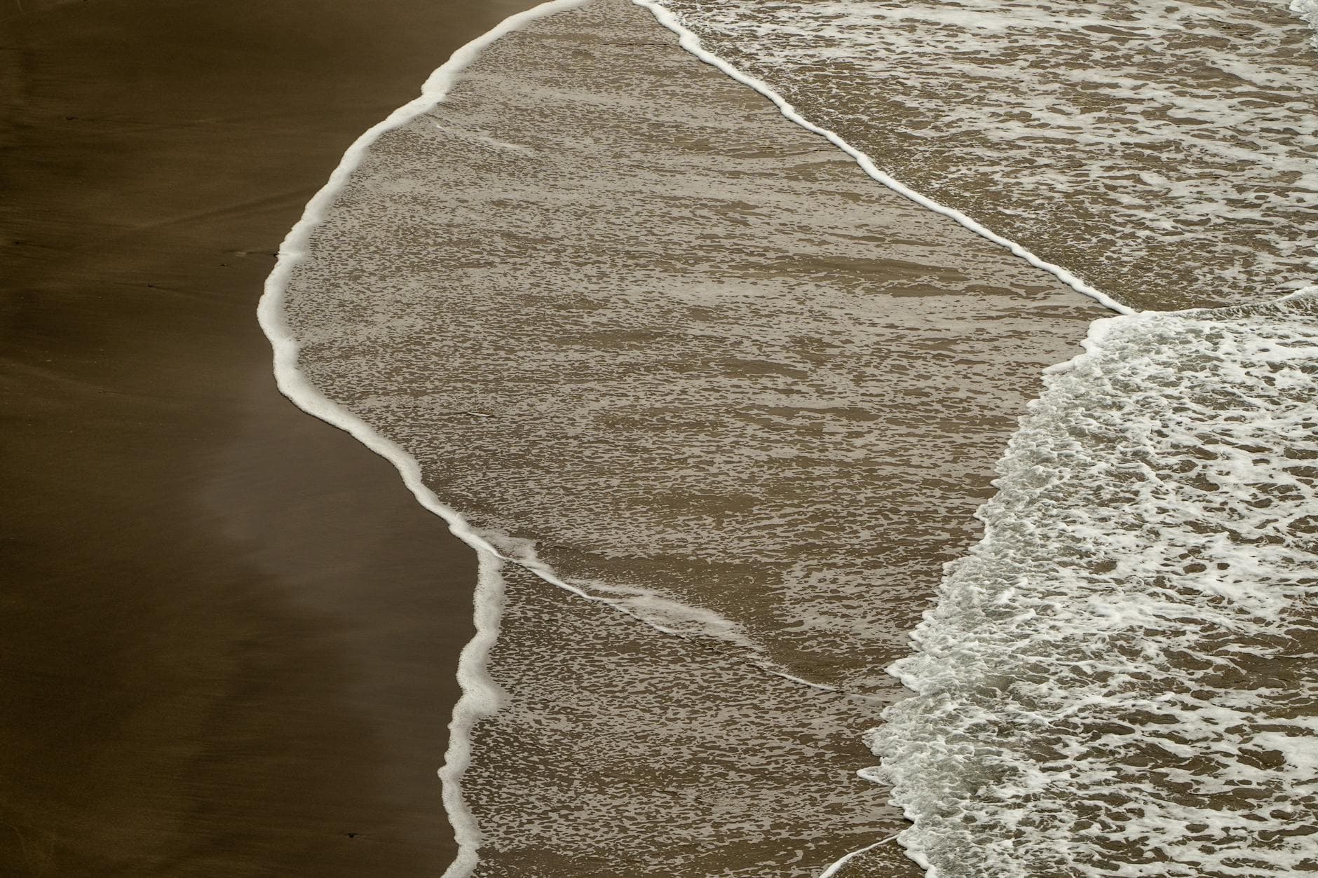 Aerial view of the gentle sea waves meeting the sandy shores of Christchurch, New Zealand.