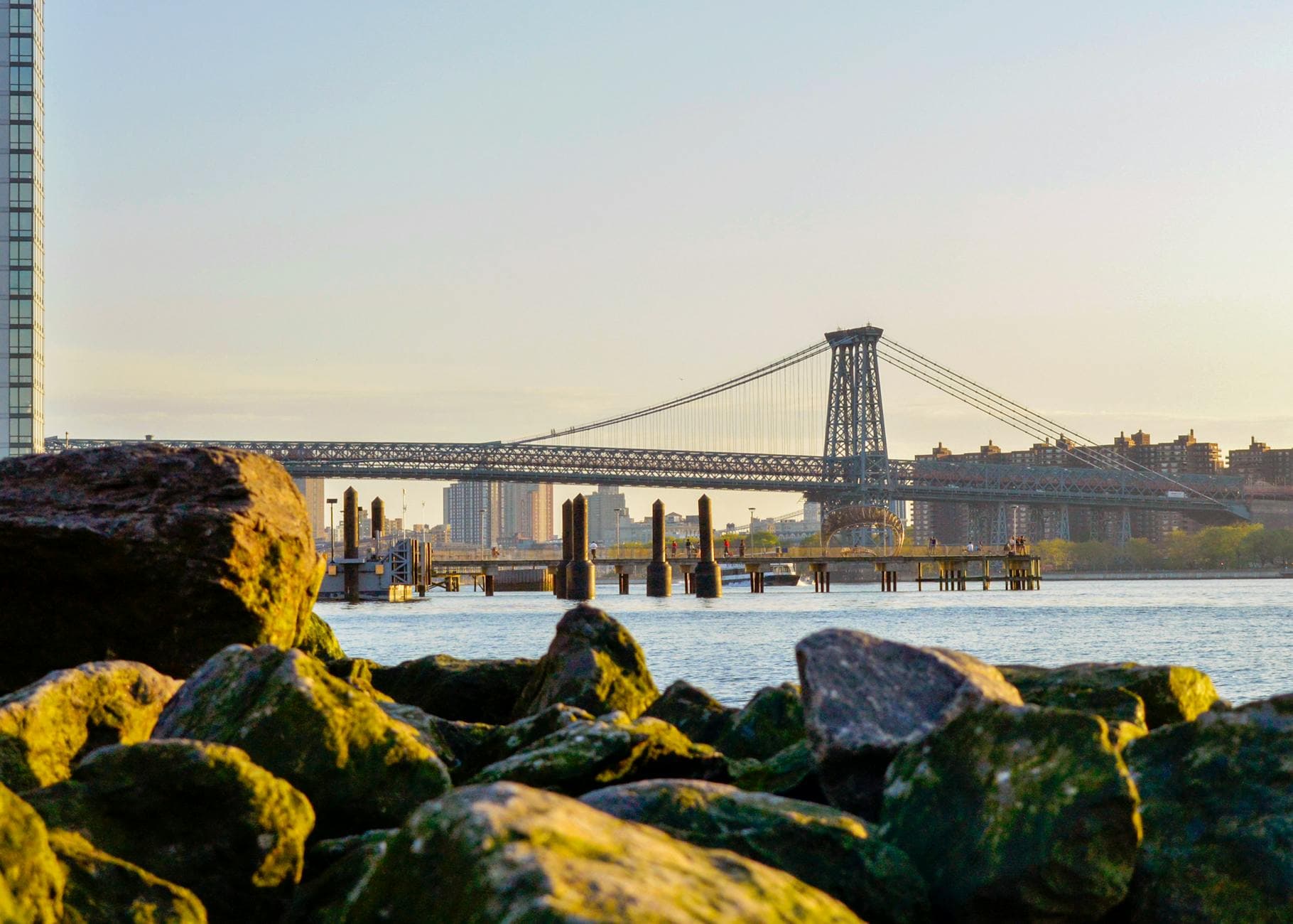 Scenic view of the Williamsburg Bridge at sunrise with the East River and waterfront in New York City.