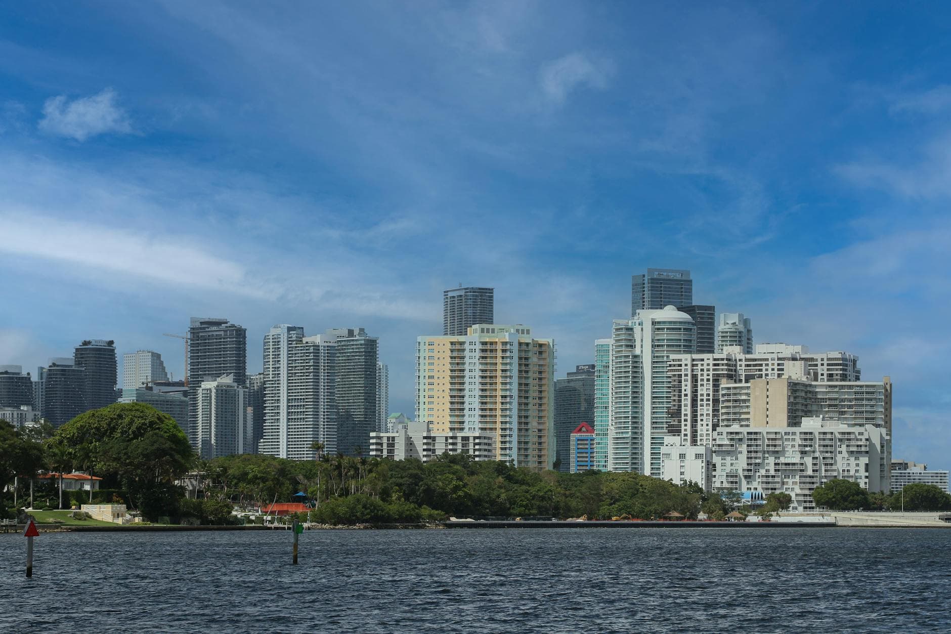 Stunning view of Miami's skyline over Biscayne Bay with clear skies and lush greenery.