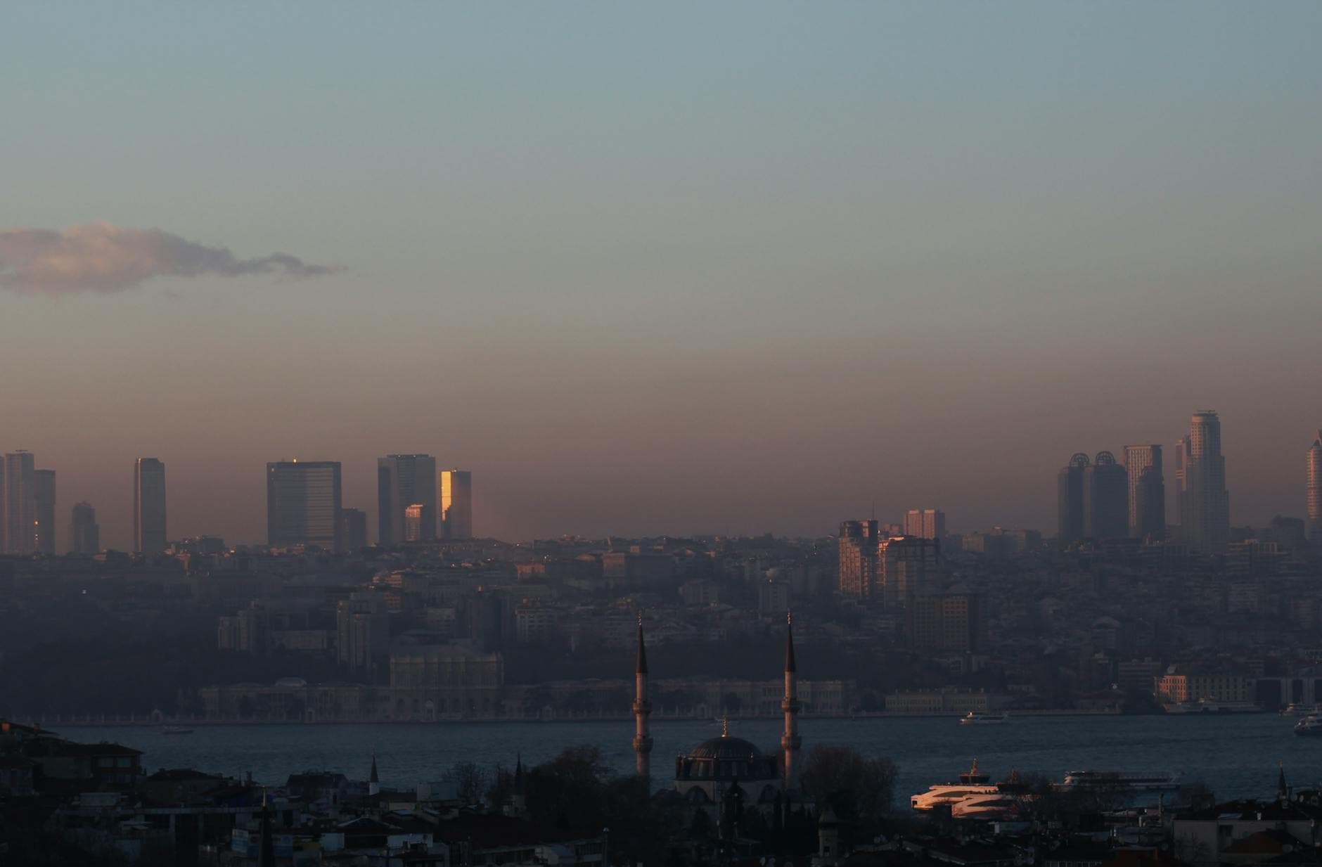 Skyline view of a city with a mosque and waterfront in Türkiye during dusk, highlighting urban life.