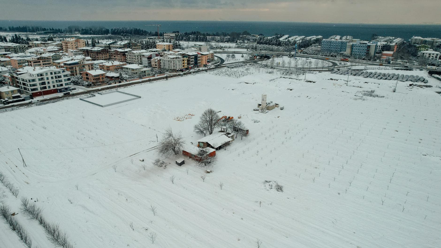 Aerial view of snow-covered fields and buildings in Yalova, Turkey during winter.