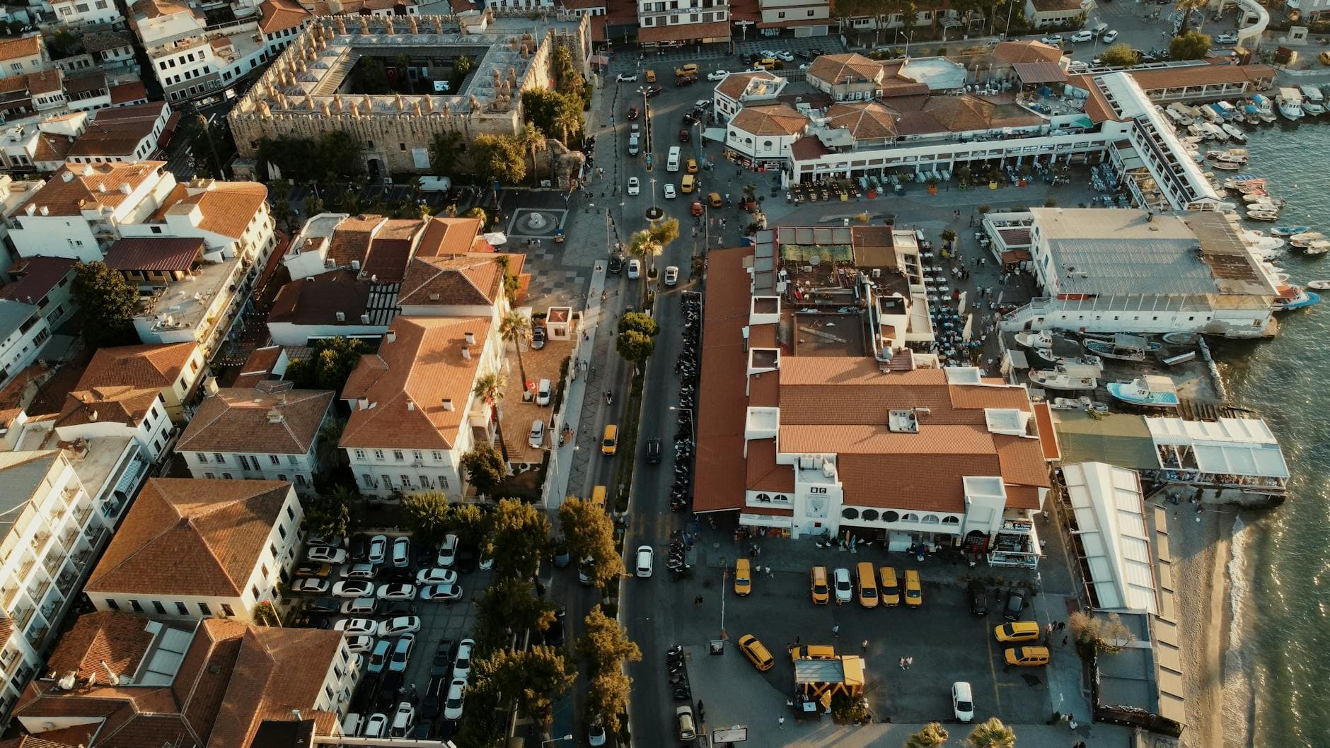 Stunning aerial view of Kuşadası, Türkiye, featuring architecture, streets, and waterfront at golden hour.