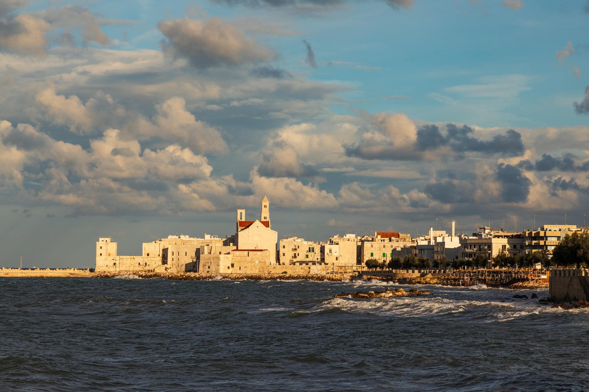 Stunning coastal view of Molfetta, Italy, under a dramatic sunset sky.