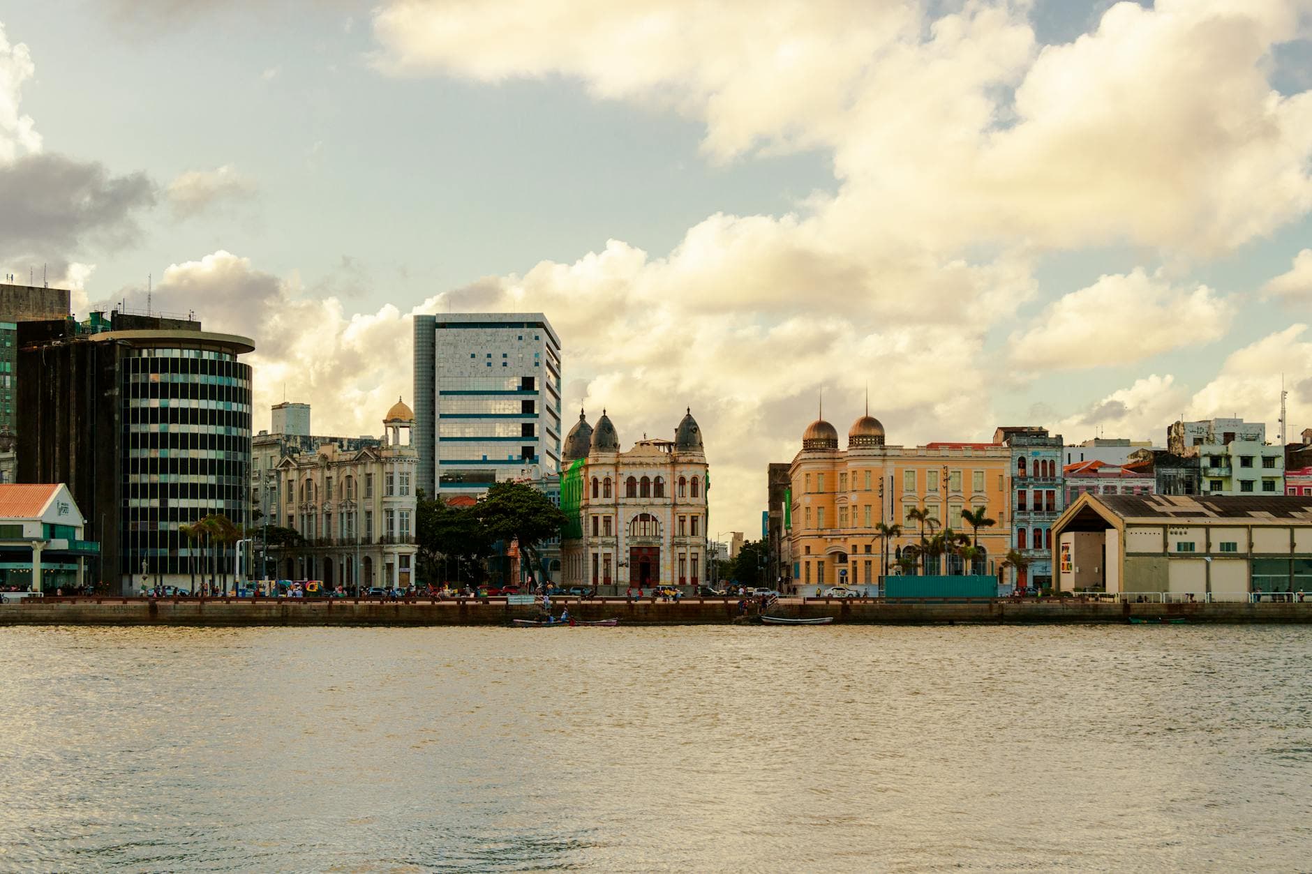 Scenic view of Recife's waterfront architecture showcasing historic and modern buildings under a partly cloudy sky.