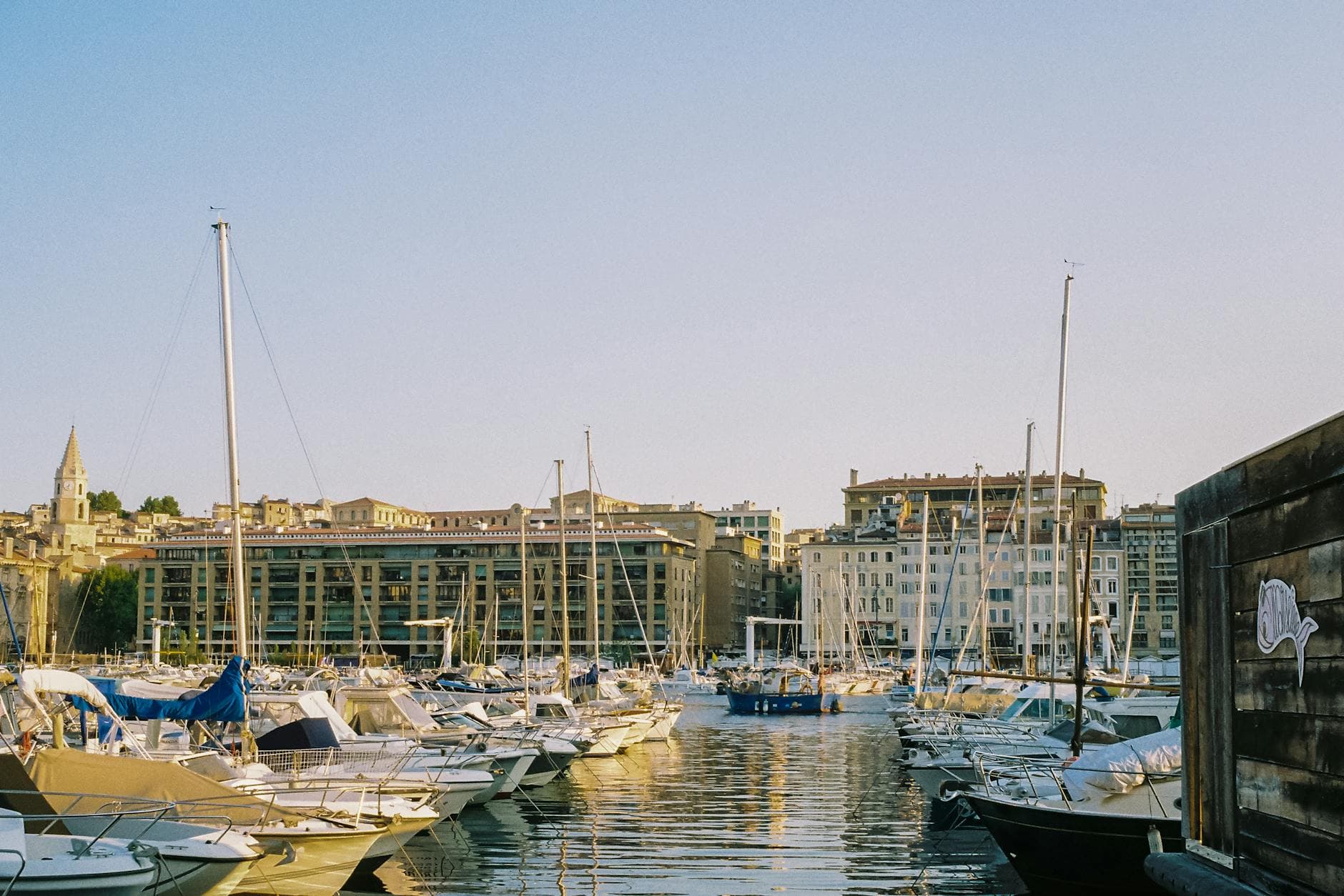 Charming view of boats in Marseille's vibrant Old Port with warm morning light and historic architecture.